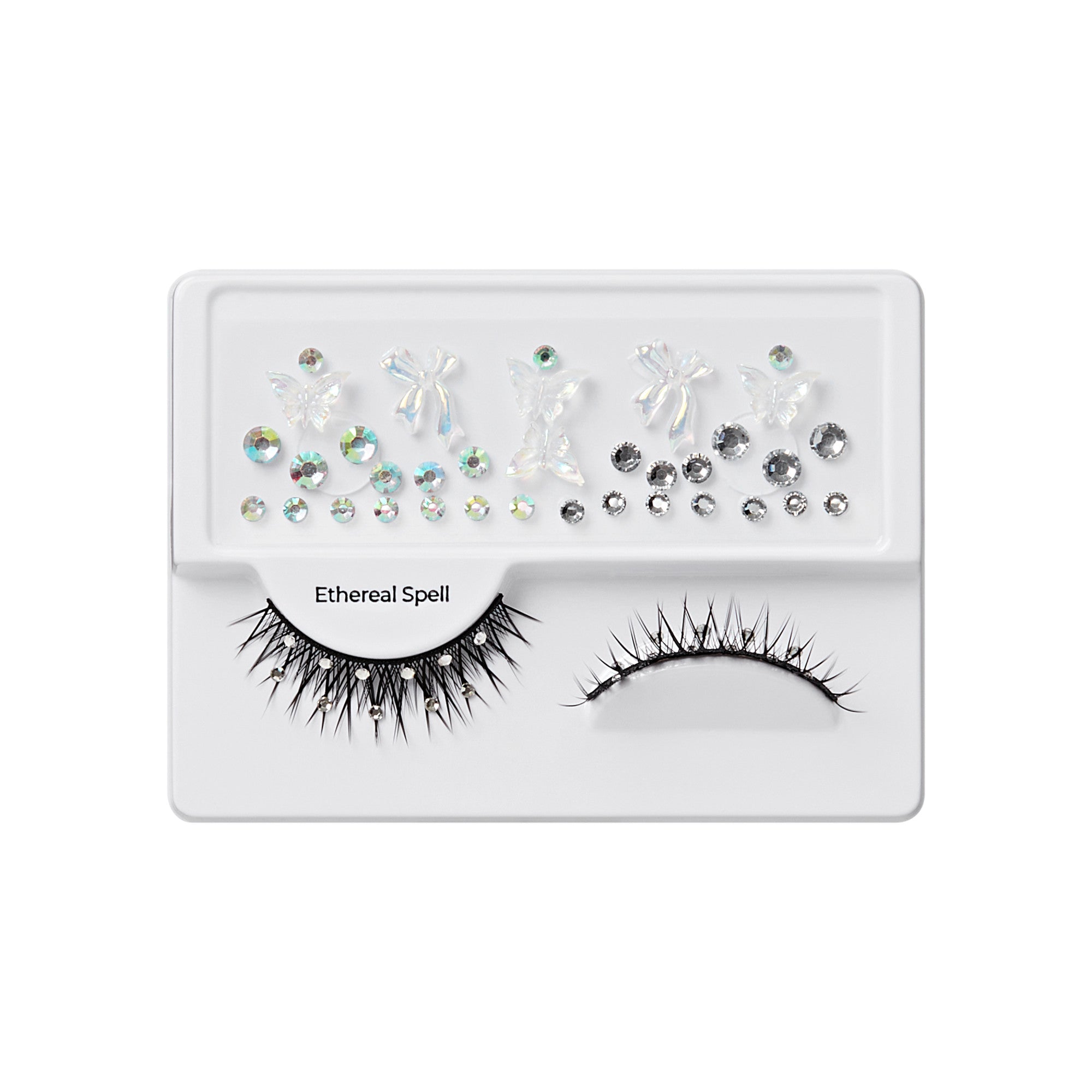 The image features a makeup product display, specifically a set of false eyelashes and decorative embellishments. The packaging is white and includes two pairs of eyelashes: one with long, spiky strands and another with a more natural look. Above the eyelashes, there are various decorative elements, including small rhinestones and shapes that resemble butterflies and other designs, all in different sizes and finishes. The set is labeled "Ethereal Spell," suggesting a whimsical or magical theme.