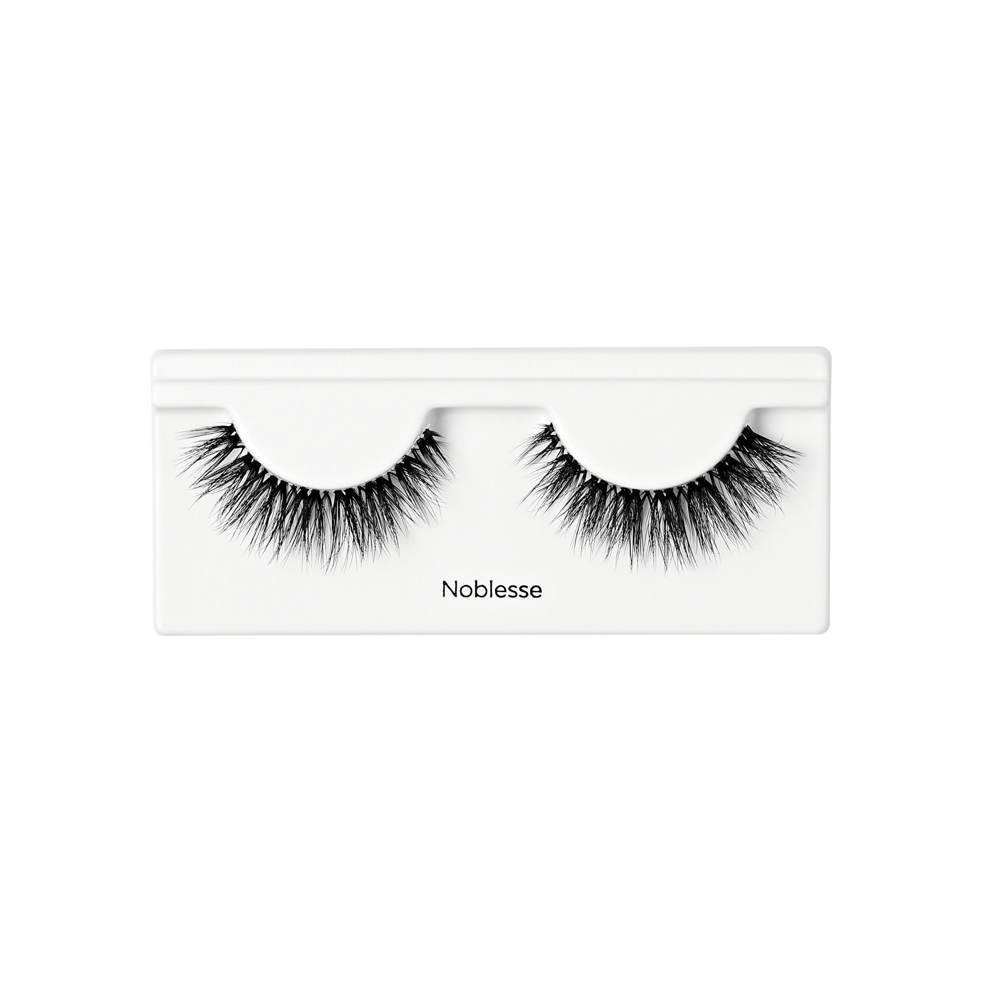 Pair of voluminous black false eyelashes with a wispy, textured design displayed in a white tray labeled \