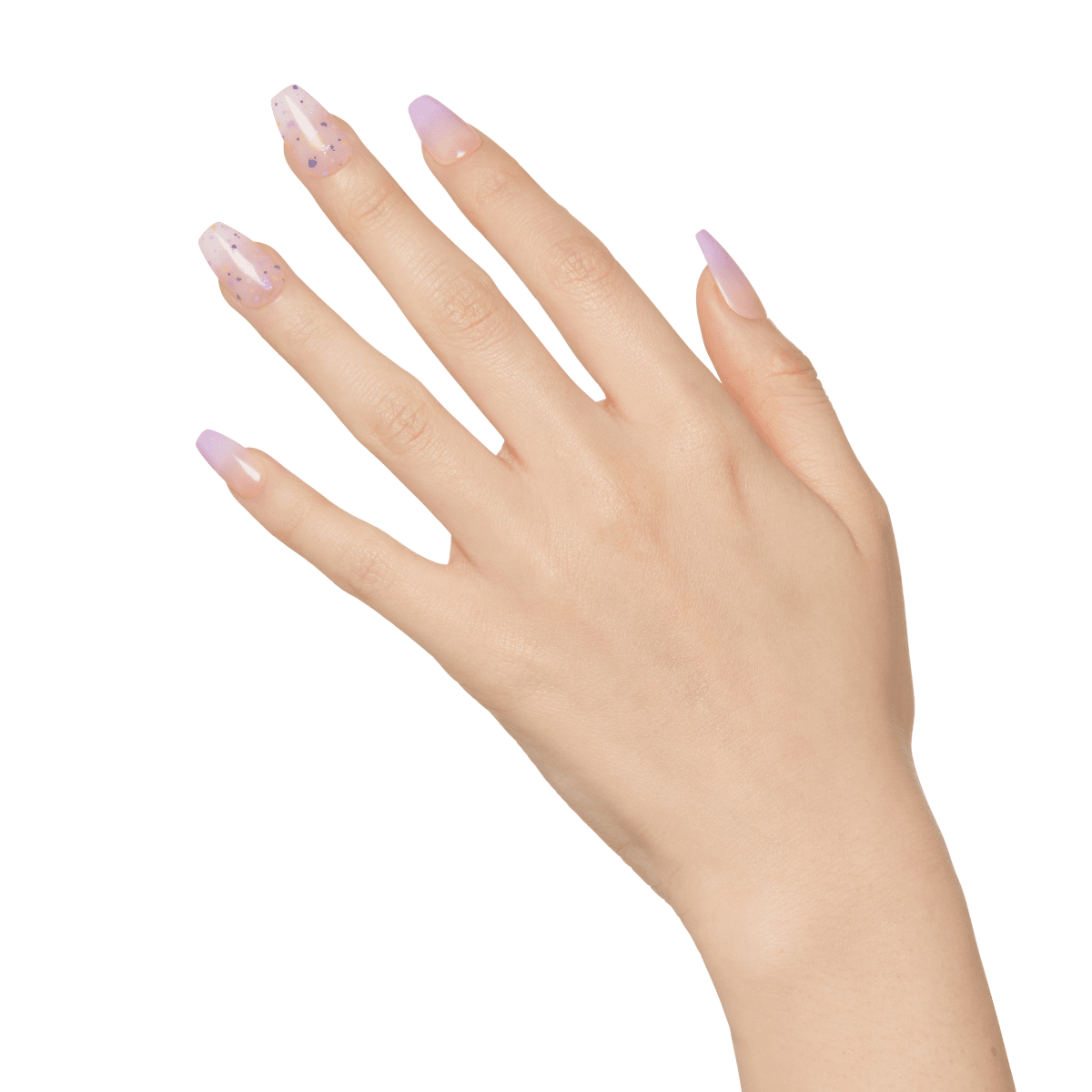 Hand with press-on manicure nails in a soft pink to nude ombre, with two nails featuring a clear base and purple glitter flakes, showing a glossy finish.