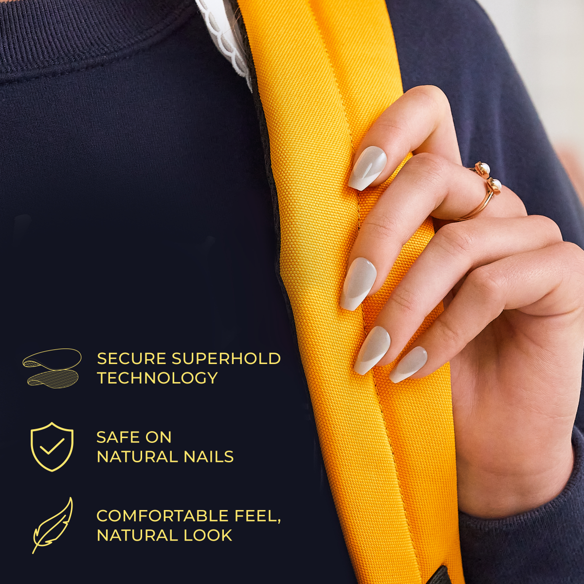 Hand with long, glossy, light gray press-on nails holding a bright yellow strap against a navy sweater. Text highlights secure superhold technology, nail safety, and natural feel.