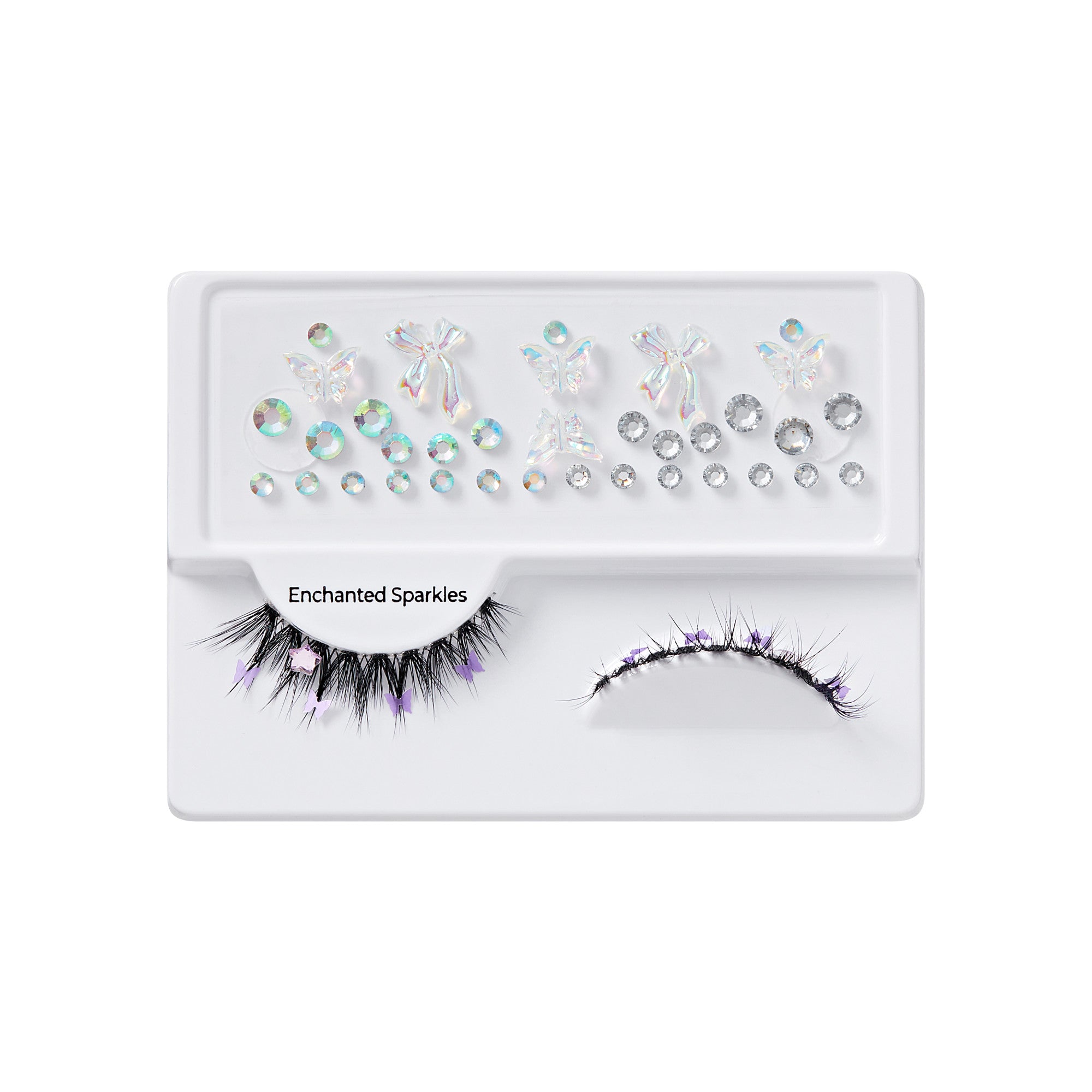Black false eyelashes decorated with small purple butterfly and star accents, accompanied by iridescent gem stickers in various shapes on a white tray labeled \