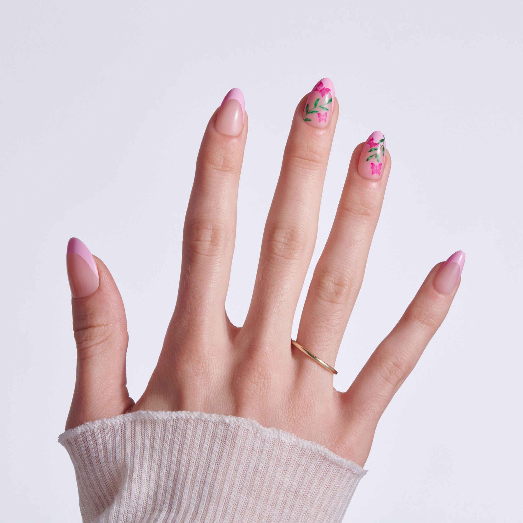 Hand displaying manicure with pink nails and floral designs on middle and ring fingers.