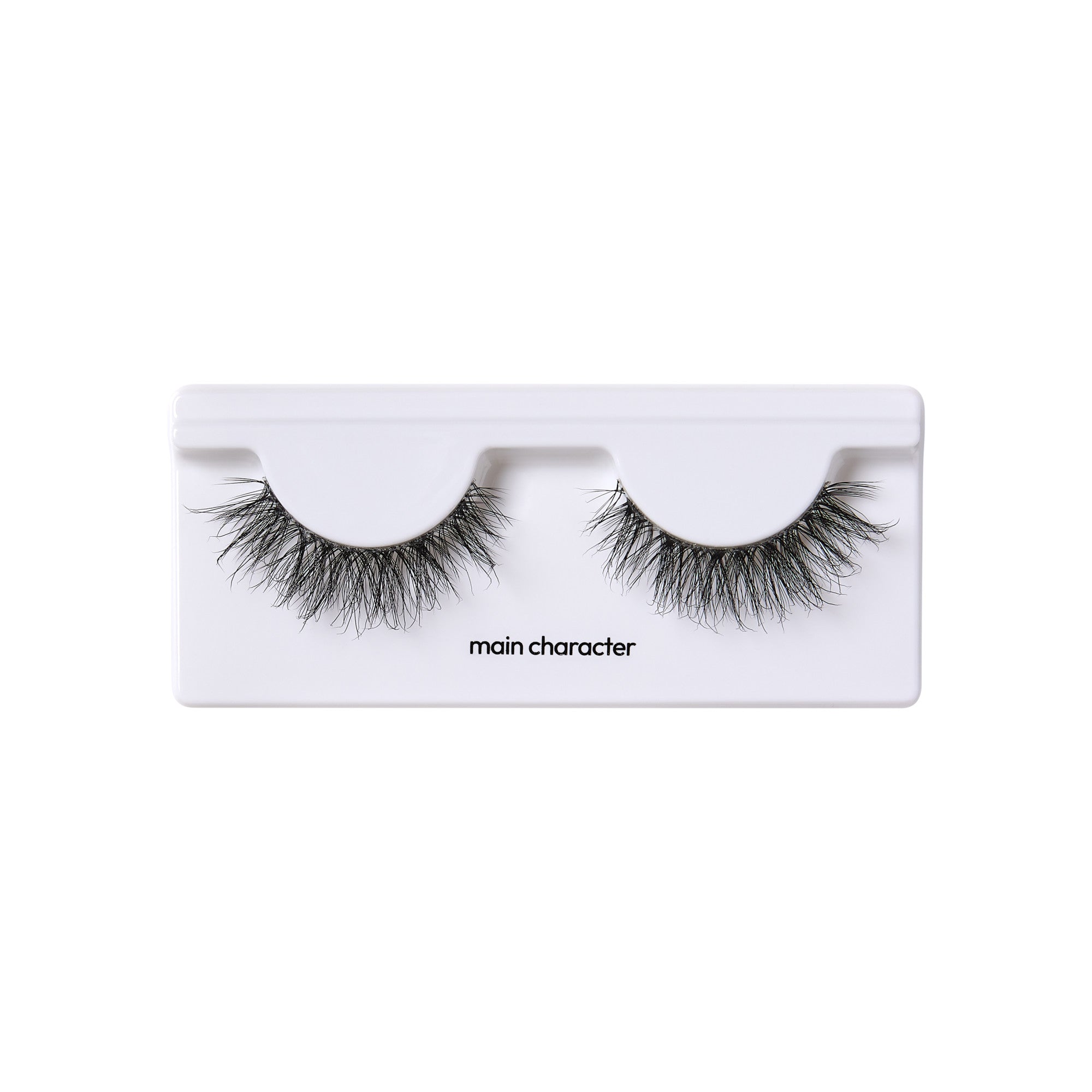 The image shows a pair of false eyelashes in a white plastic case. The eyelashes are thick and voluminous, with a wispy, natural look. The case has two semi-circular indentations where the eyelashes are placed. Below the indentations, the text "main character" is printed in black. The overall presentation is clean and minimalistic.