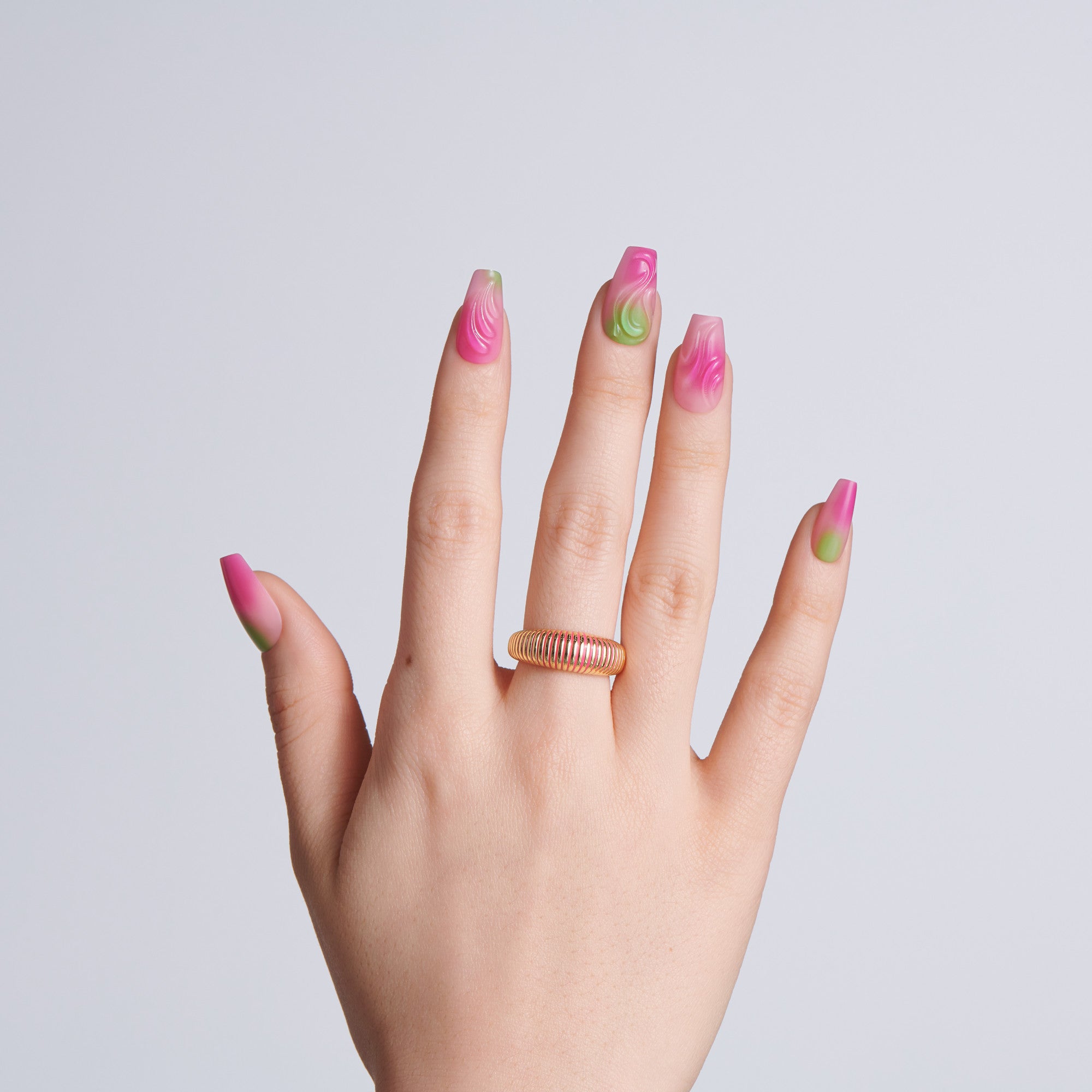 Hand with pink and green nail polish on a plain background