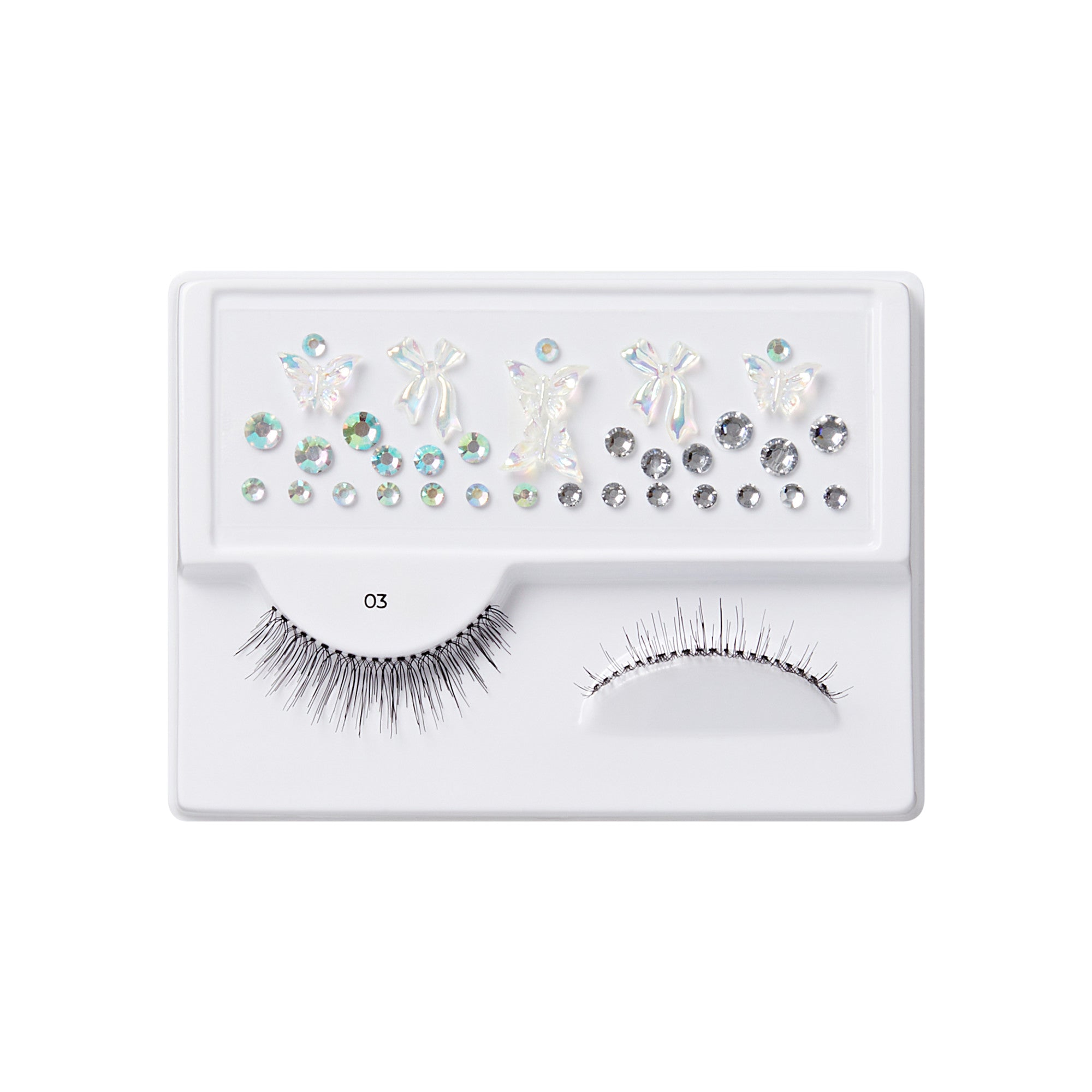 The image features a makeup accessory set displayed on a white tray. It includes a pair of false eyelashes with a dramatic, spiky design on the left side. Next to the lashes, there are various decorative elements, including iridescent butterfly shapes and sparkling rhinestones in different sizes and shapes. The overall presentation is organized and visually appealing, showcasing items that can enhance eye makeup looks.