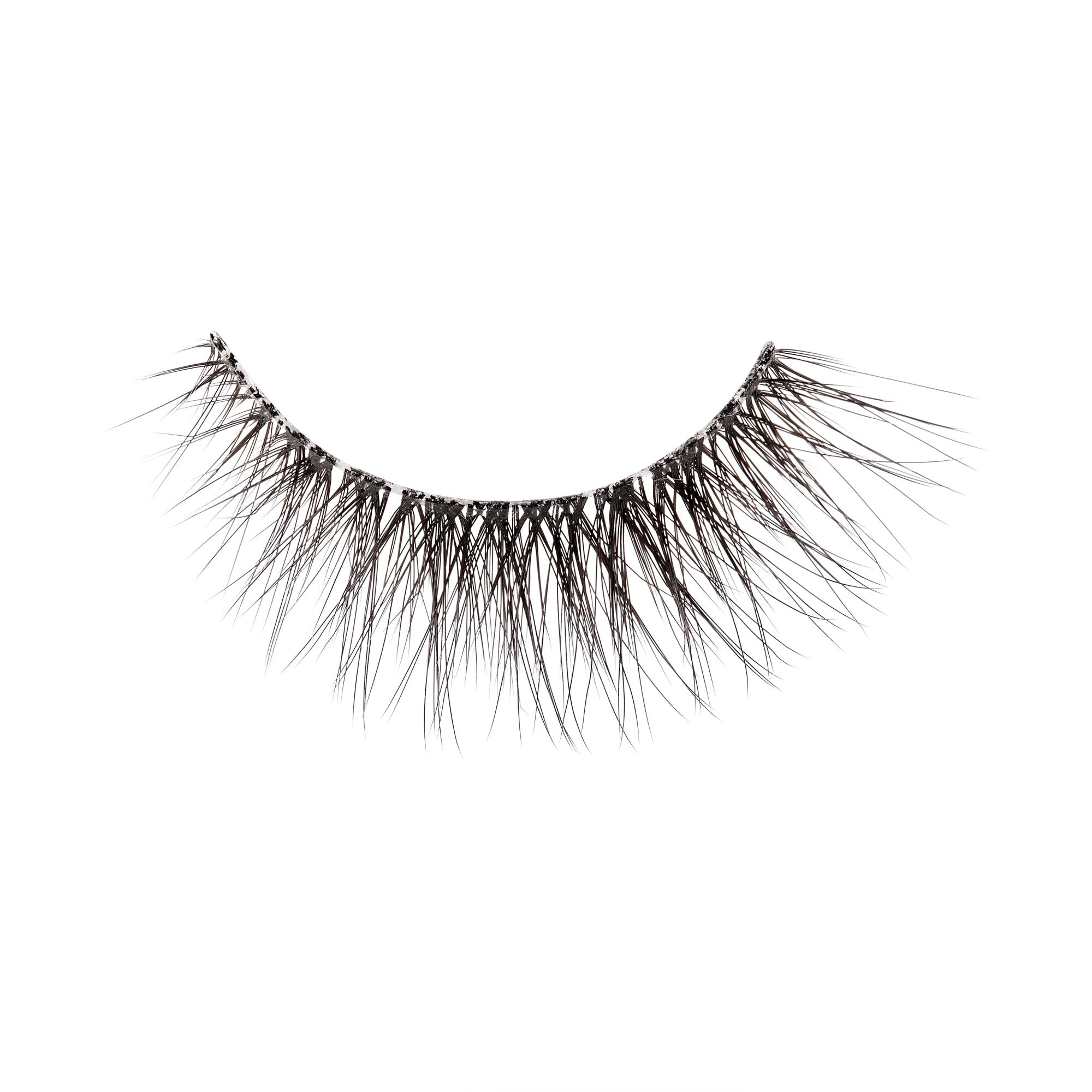 The image shows a single false eyelash. The eyelash is curved and features a dense arrangement of fine, black synthetic fibers that taper to a point, mimicking the appearance of natural eyelashes. The base of the eyelash is thicker and darker, designed to adhere to the eyelid. The fibers are arranged in a way that provides a voluminous and dramatic look. The background of the image is plain white, highlighting the details of the eyelash.