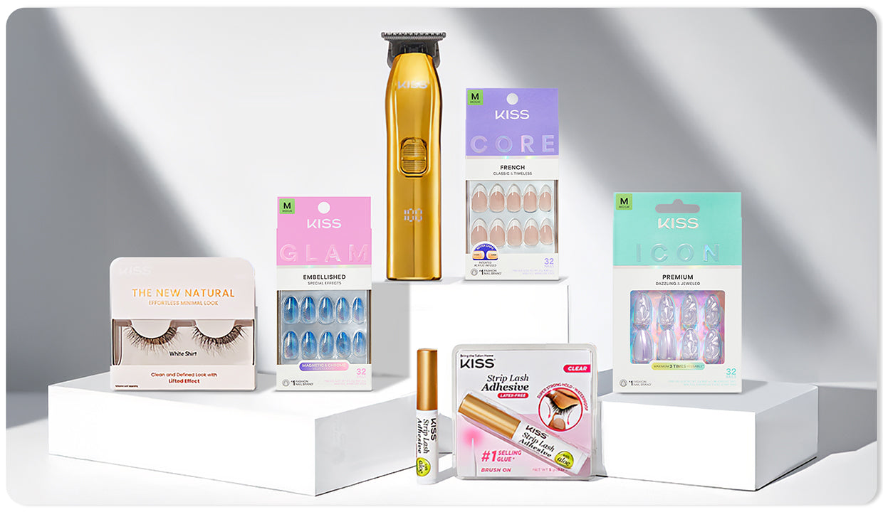 KISS beauty products including golden trimmer, three sets of press-on nails in pink, purple, and teal packaging, eyelash adhesive, and natural false lashes displayed on white podiums.