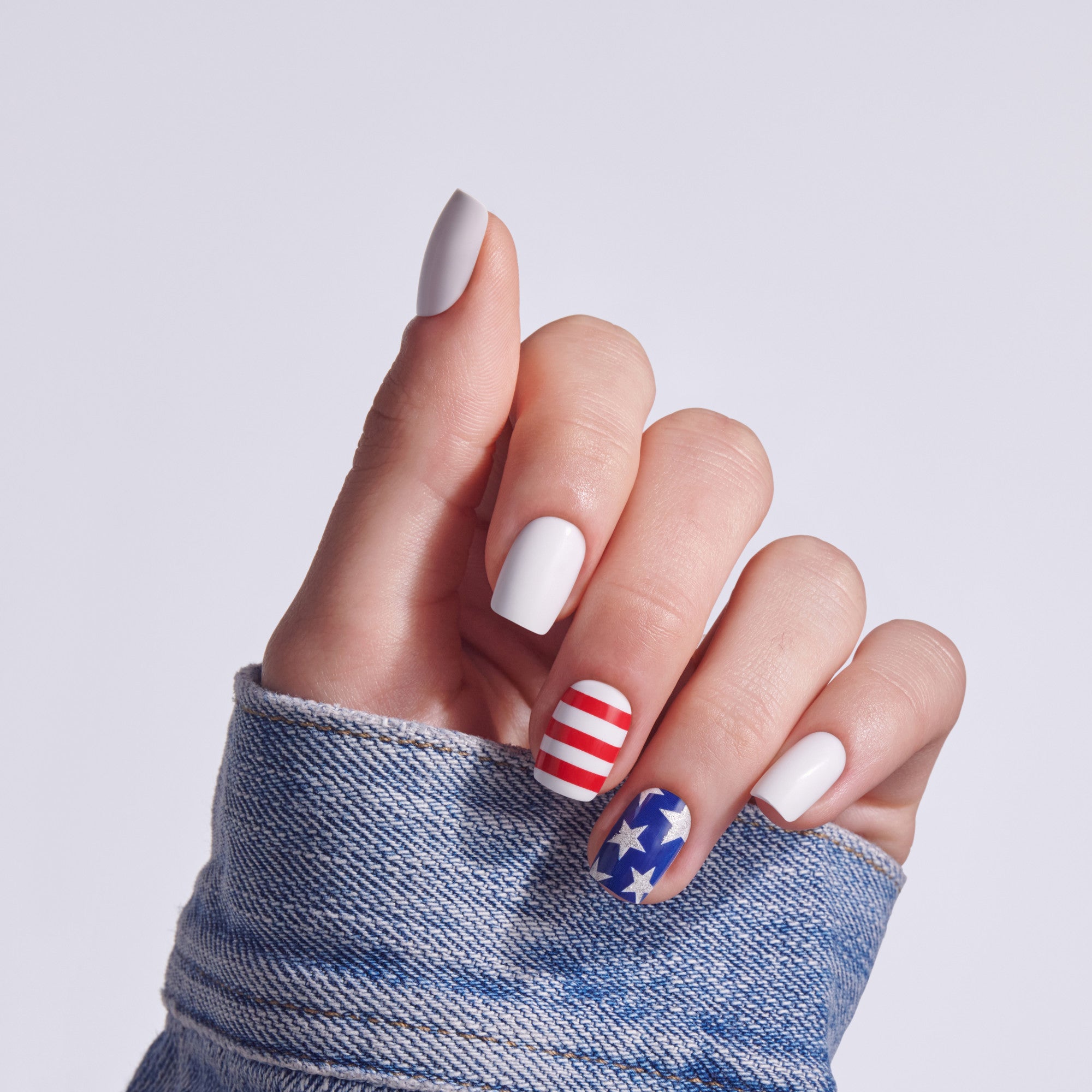 Patriotic nail design with red-white stripes, white, and blue stars on short nails.