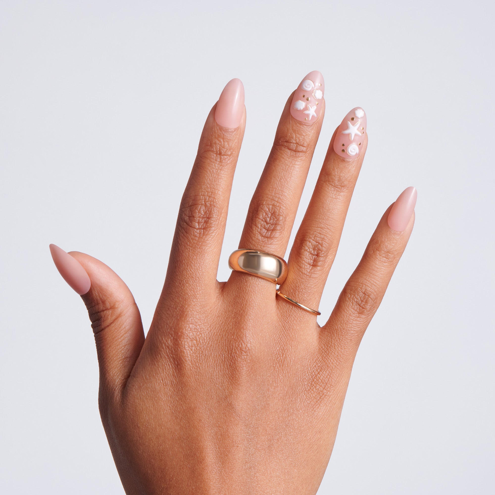Hand wearing a gold ring with a plain background