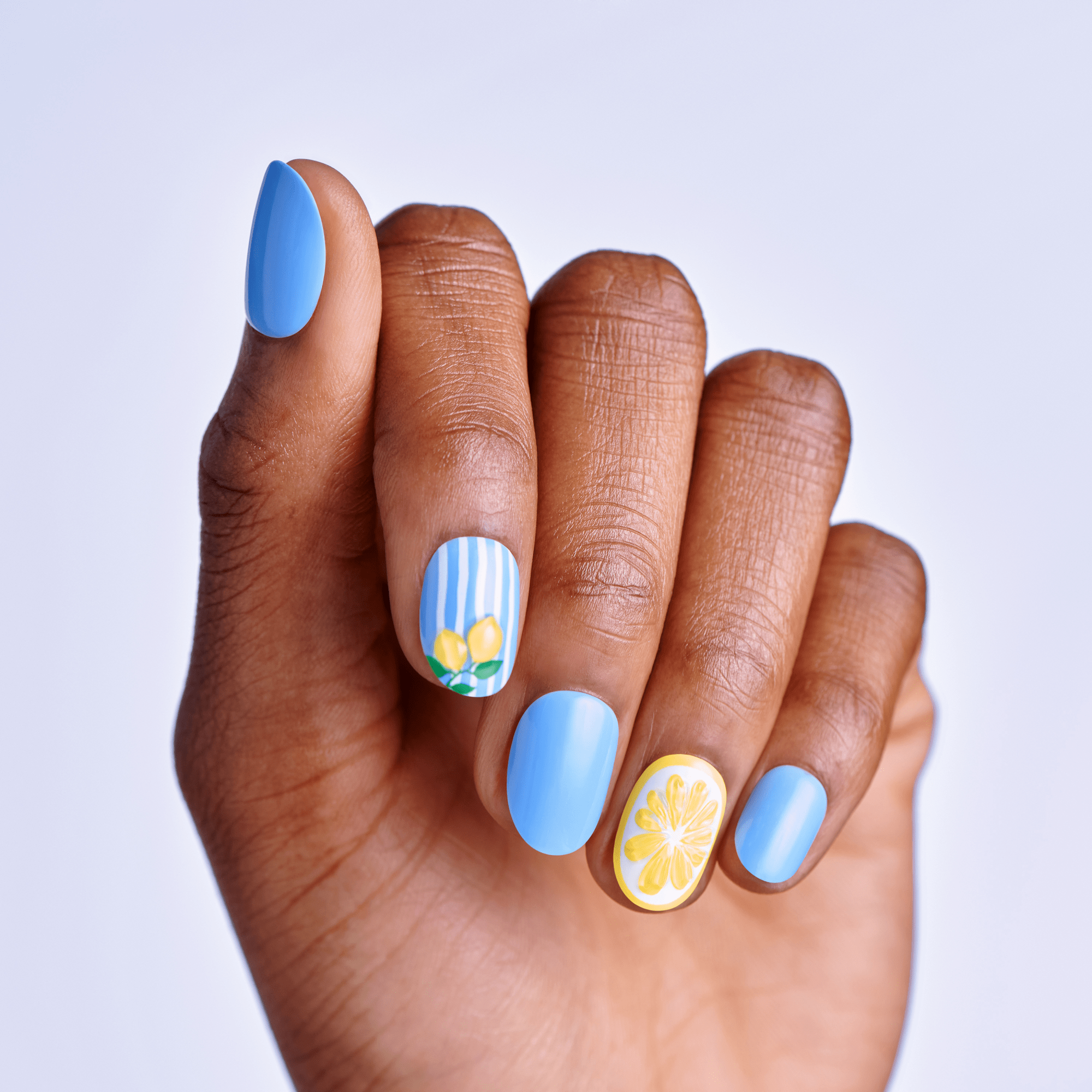 Hand with blue nail polish and floral designs on a light gray background