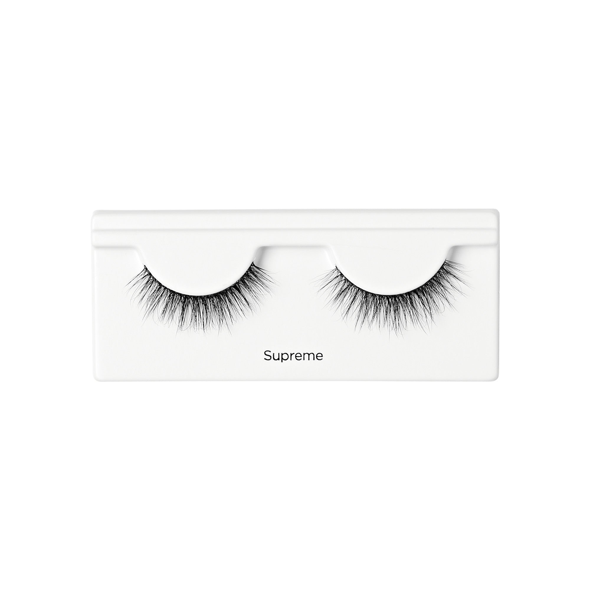 Pair of black, voluminous false eyelashes with varying lengths arranged in a white plastic tray labeled \