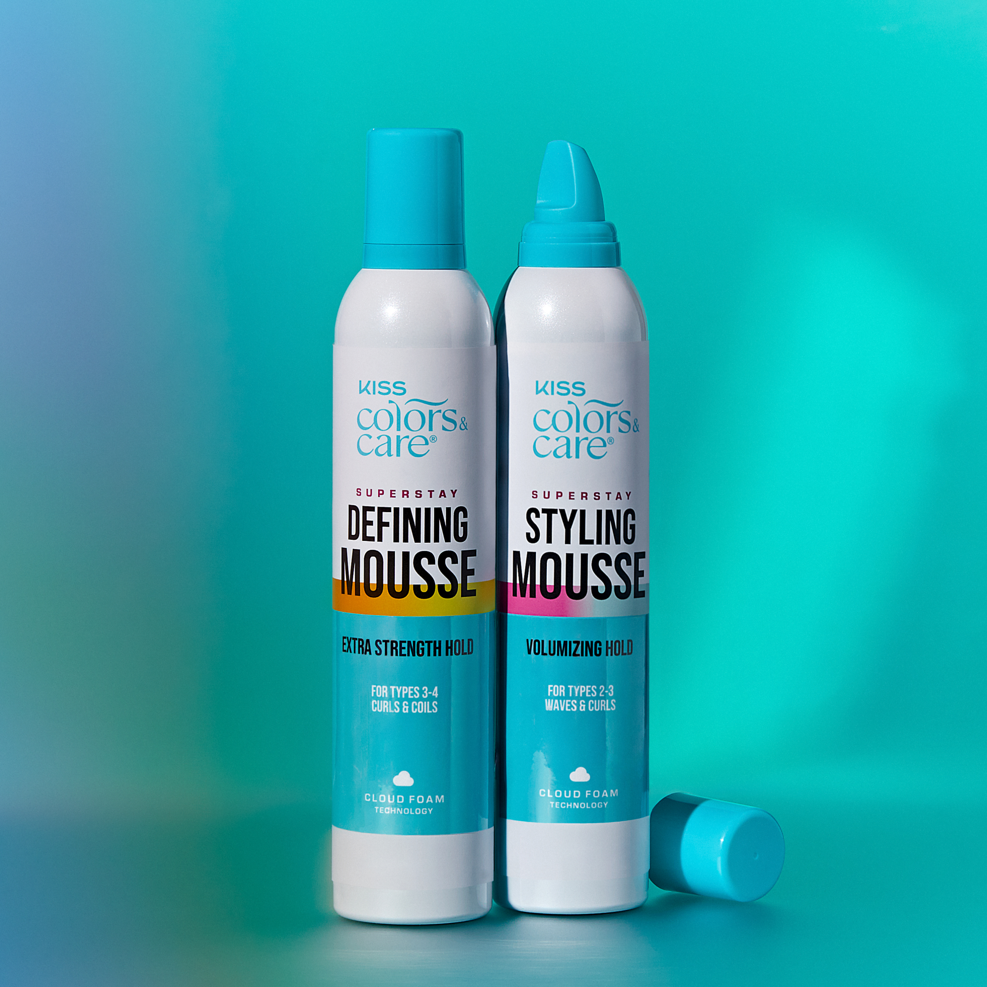 Two white and turquoise cans of KISS Colors & Care Superstay hair mousse on a blue-green background; one for extra strength hold curls 3-4, the other for volumizing hold waves and curls 2-3.