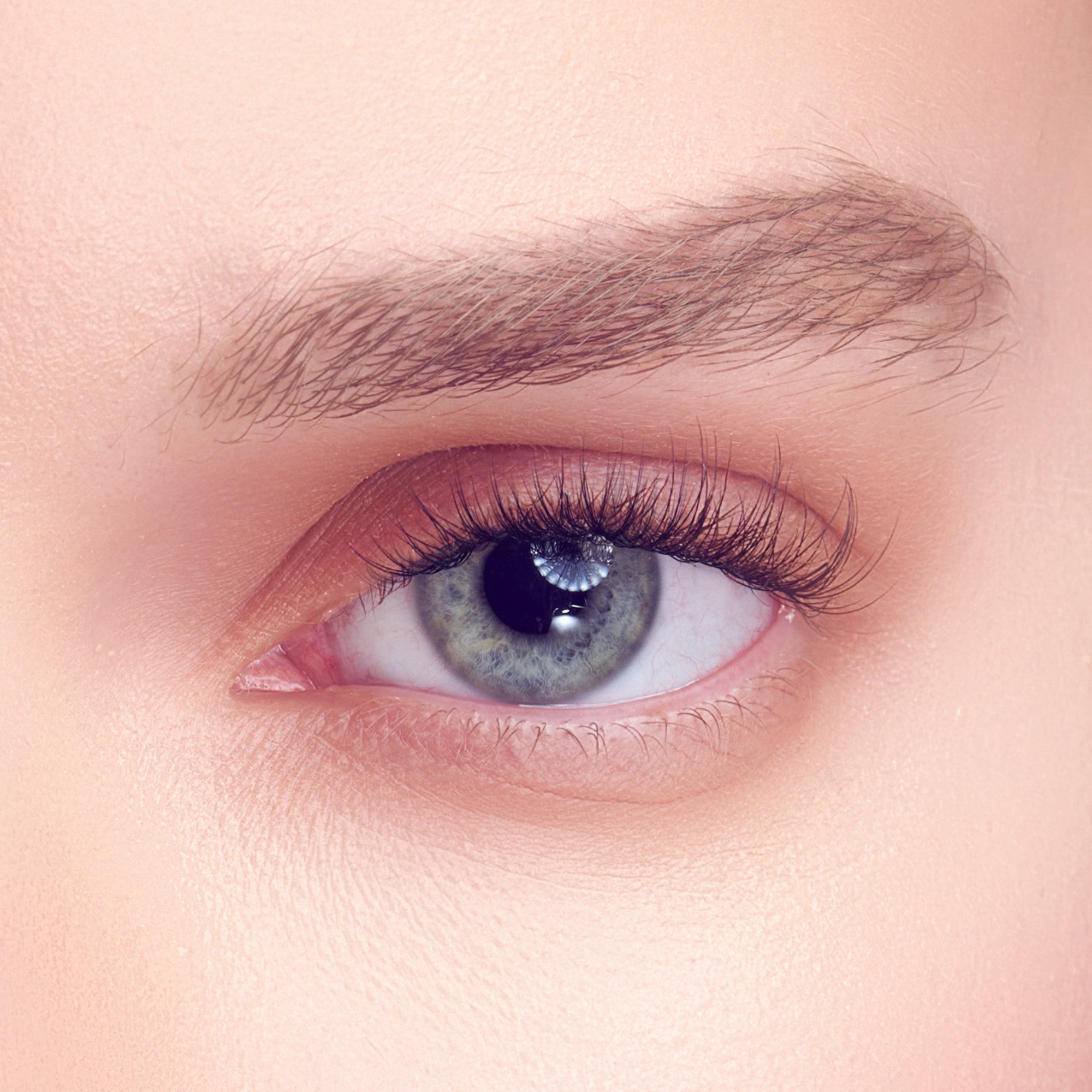 Close-up of a light-skinned eye with natural-looking, delicate eyelash extensions enhancing length and curl on the upper lashes.