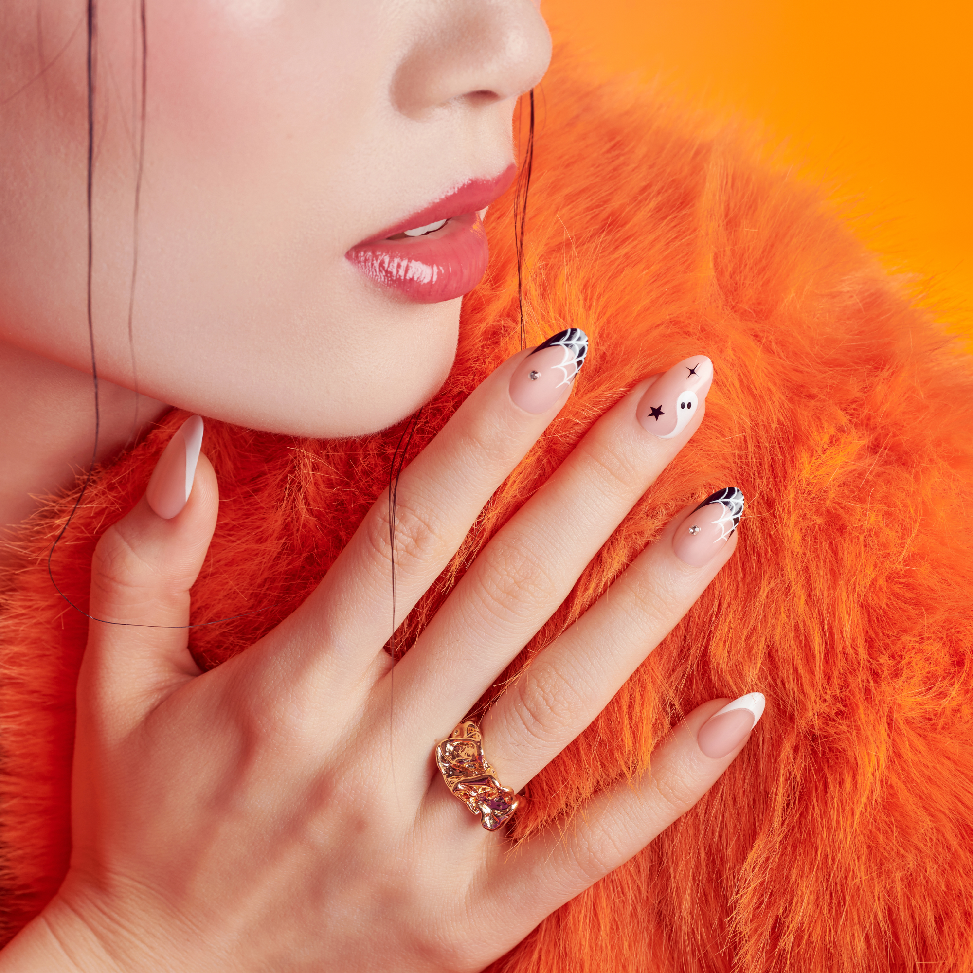 Close-up of a hand with decorative nails and a ring on an orange background