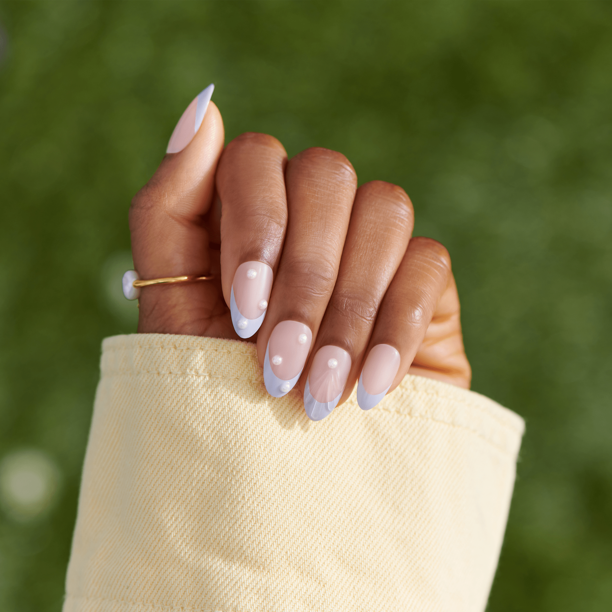 Almond nails with lavender ombré and white polka dots, gold ring, yellow sweater.