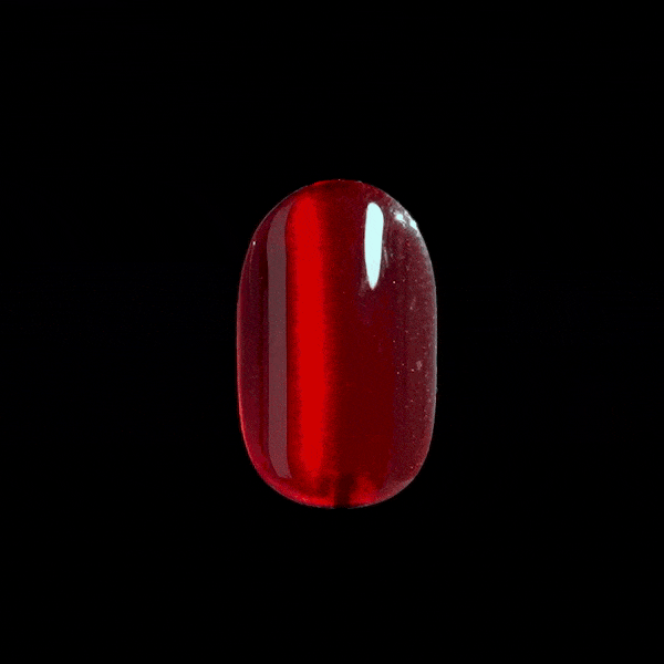 Single glossy press-on nail in deep translucent red with a high shine finish, shown rotating against a black background.