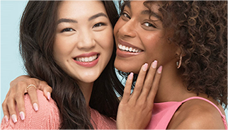 Two women smiling and embracing, showing off manicured nails from the KISS brand