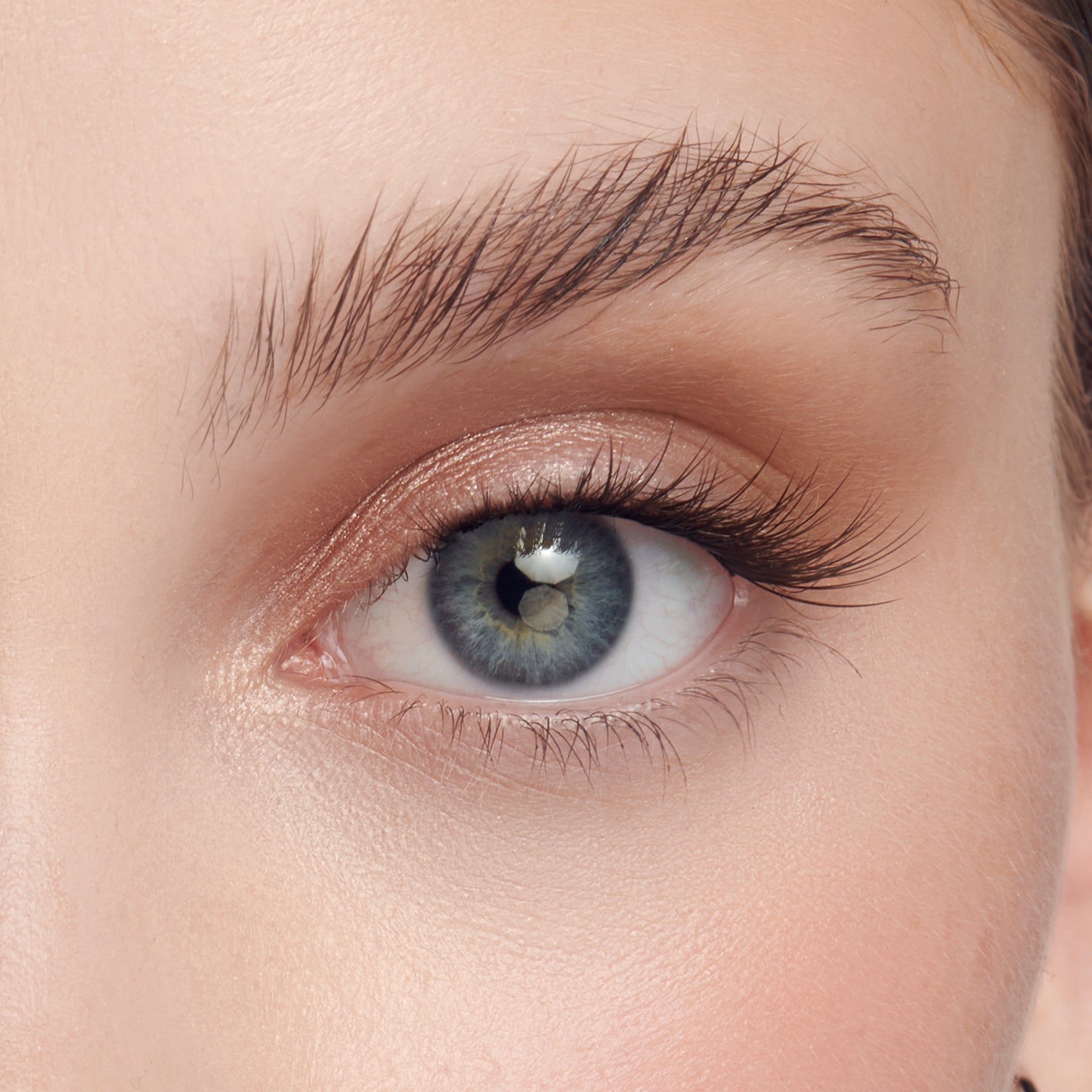 Close-up of a blue eye with natural skin tone, wearing black wispy false eyelashes that enhance the lash length and volume.