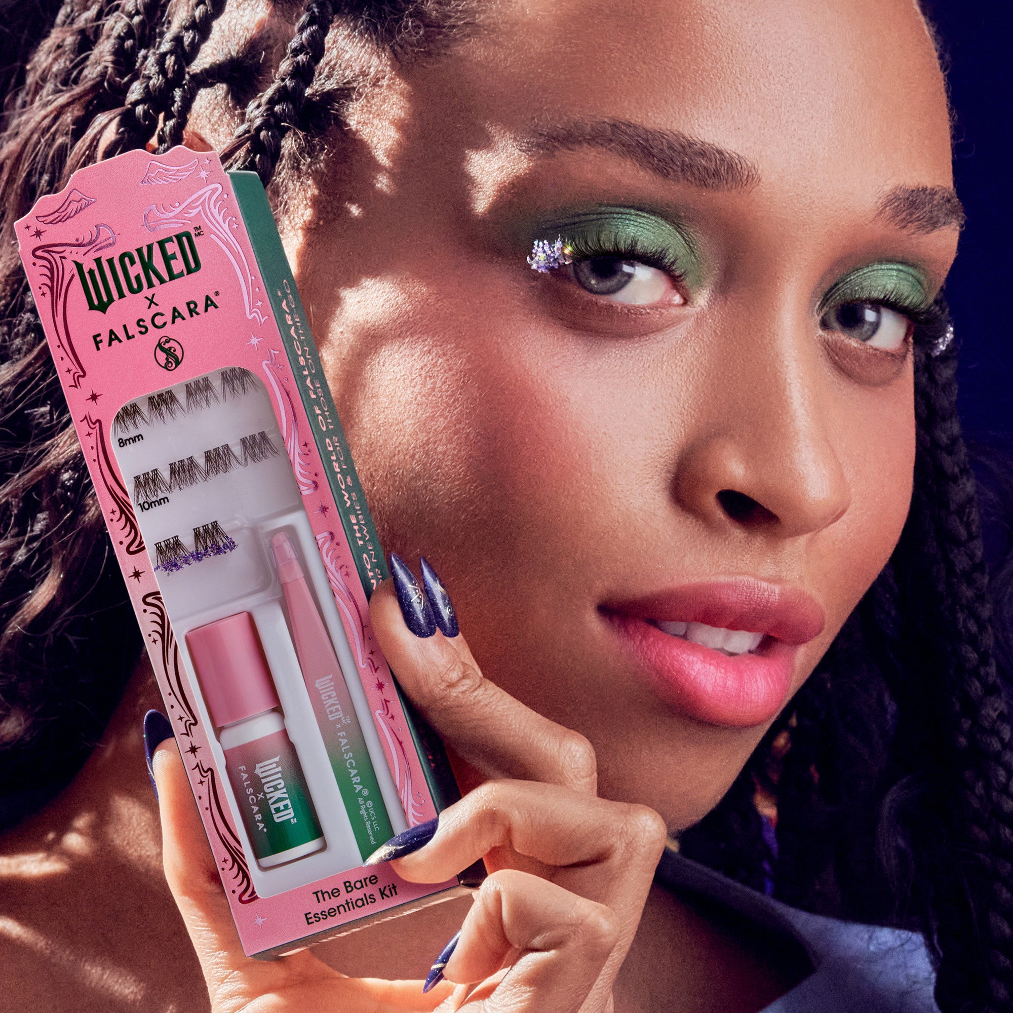 Close-up of a woman with braided hair holding WICKED X FALSCARA False Eyelashes Darlingest kit featuring three lash sizes, adhesive, and applicator in pink and green packaging labeled \