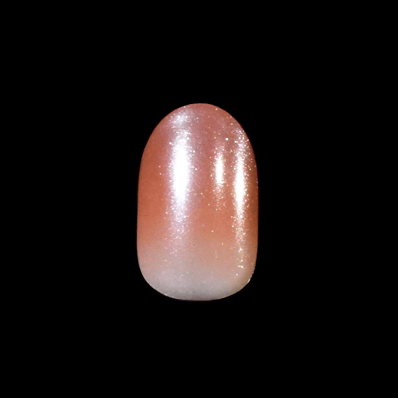 Single press-on nail with a glossy, gradient finish transitioning from soft peach to light pink, sprinkled with fine silver glitter.