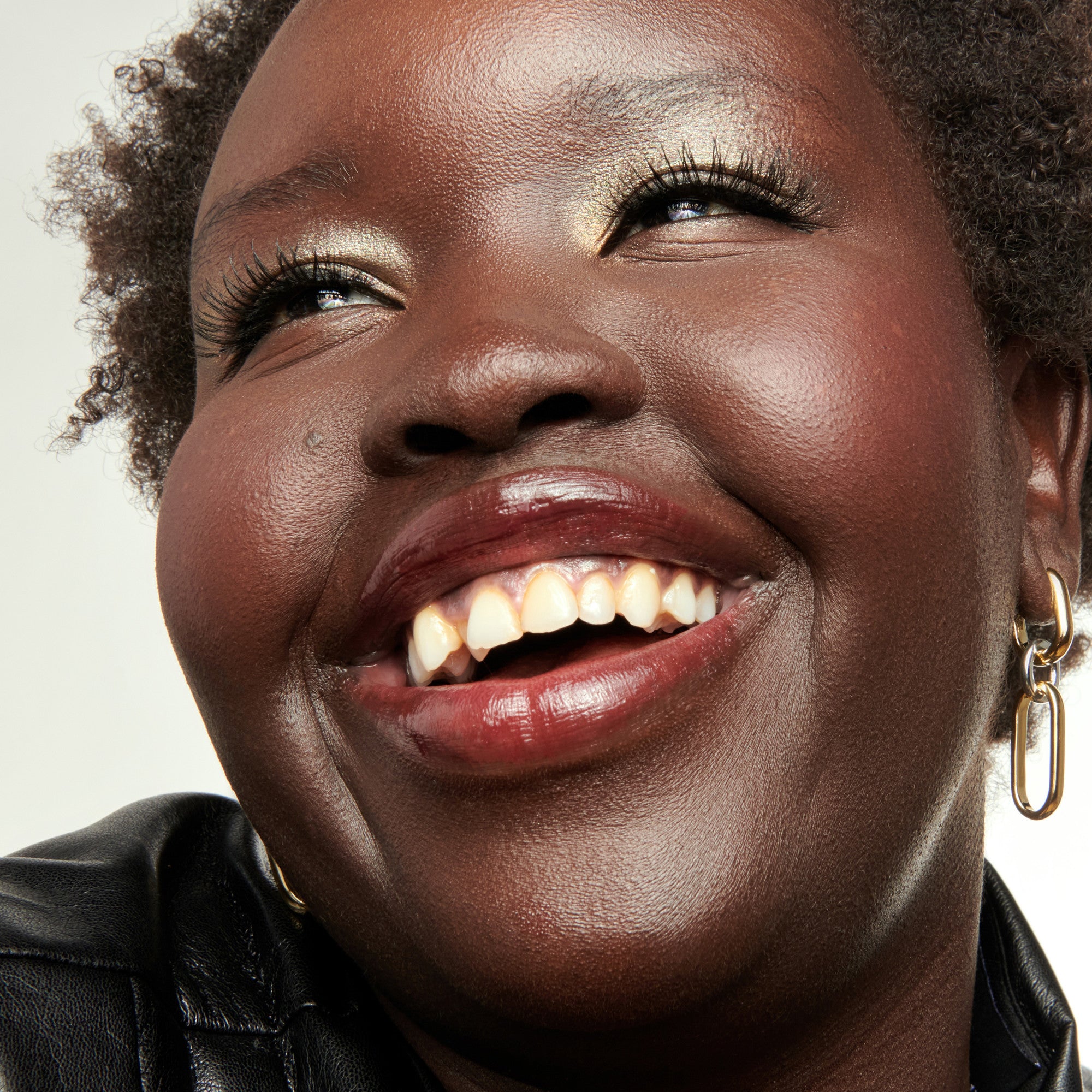 Close-up of a woman with a warm smile against a neutral background
