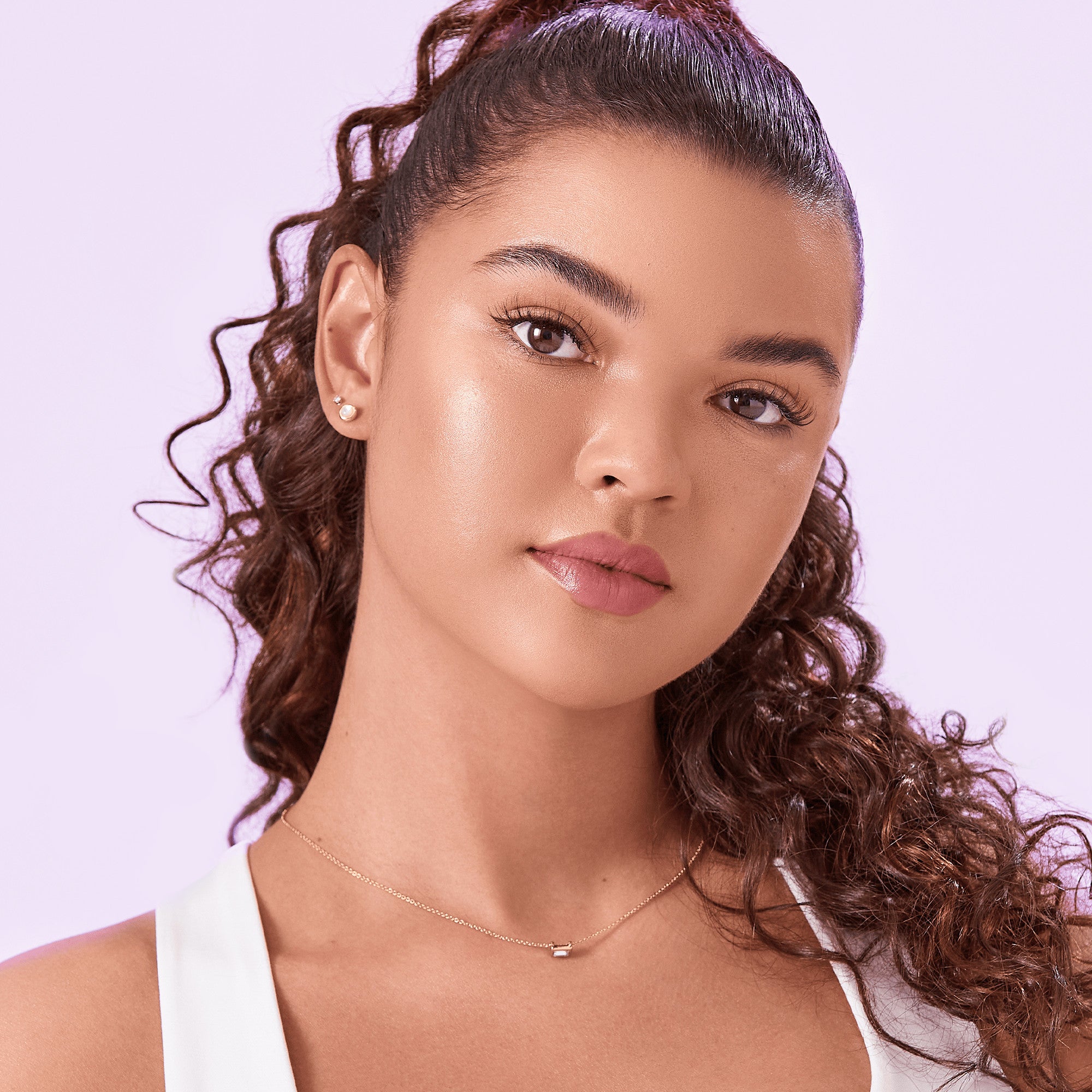 Close-up of a woman with smooth skin, natural makeup, and curled hair wearing imPRESS Falsies self-adhesive eyelashes that enhance the length and volume of her lashes.