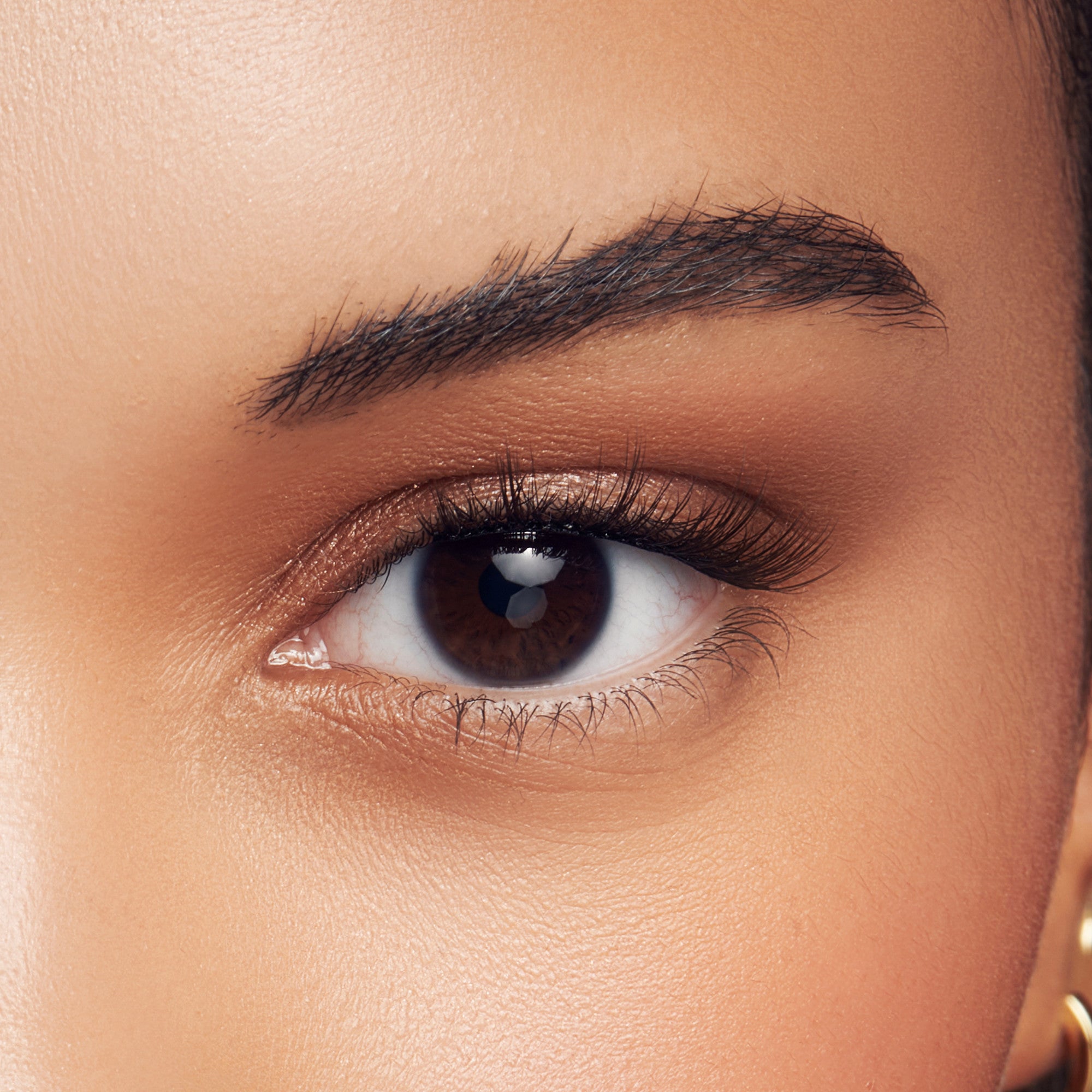 Close-up of a brown eye with natural-looking, full self-adhesive false eyelashes applied, showcasing the modern natural style effect.