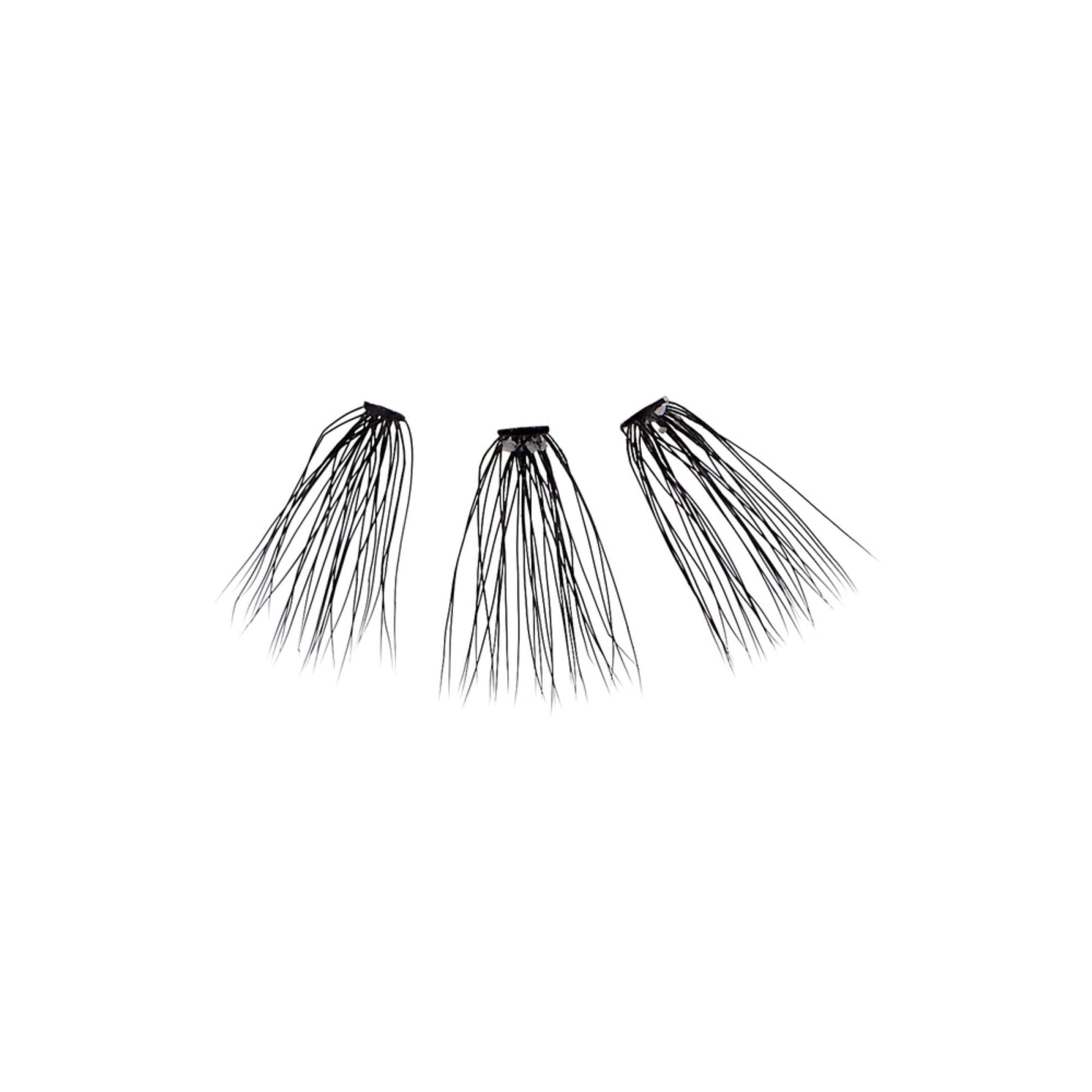 Three clusters of thin, long, black individual eyelash extensions spread out against a white background, part of the KISS Lash Couture Luxtensions Kit.