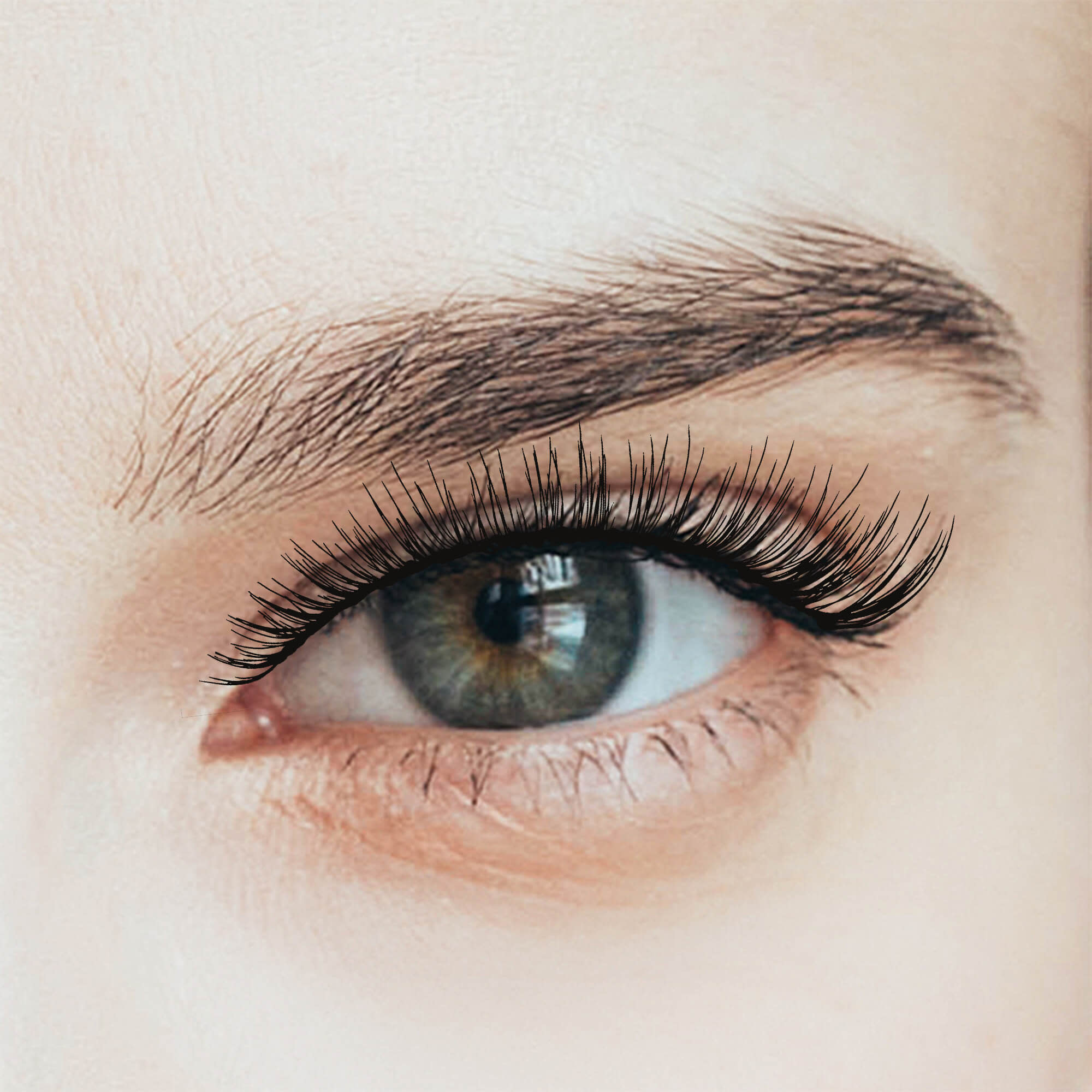 Close-up of a green eye with long, full, natural-looking false eyelashes applied, enhancing the lash line with a sultry effect.