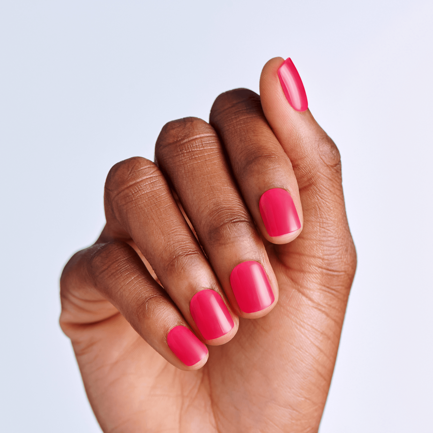 Hand with pink press on nails on a light purple background