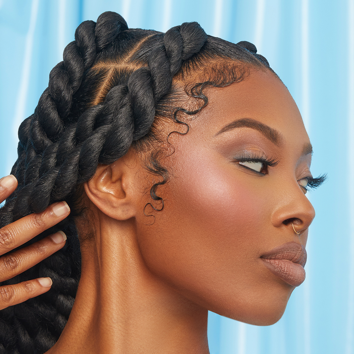 Close-up profile of a woman with smooth, styled twists and well-defined, sleek baby hairs against a light blue background, highlighting polished hair edges.