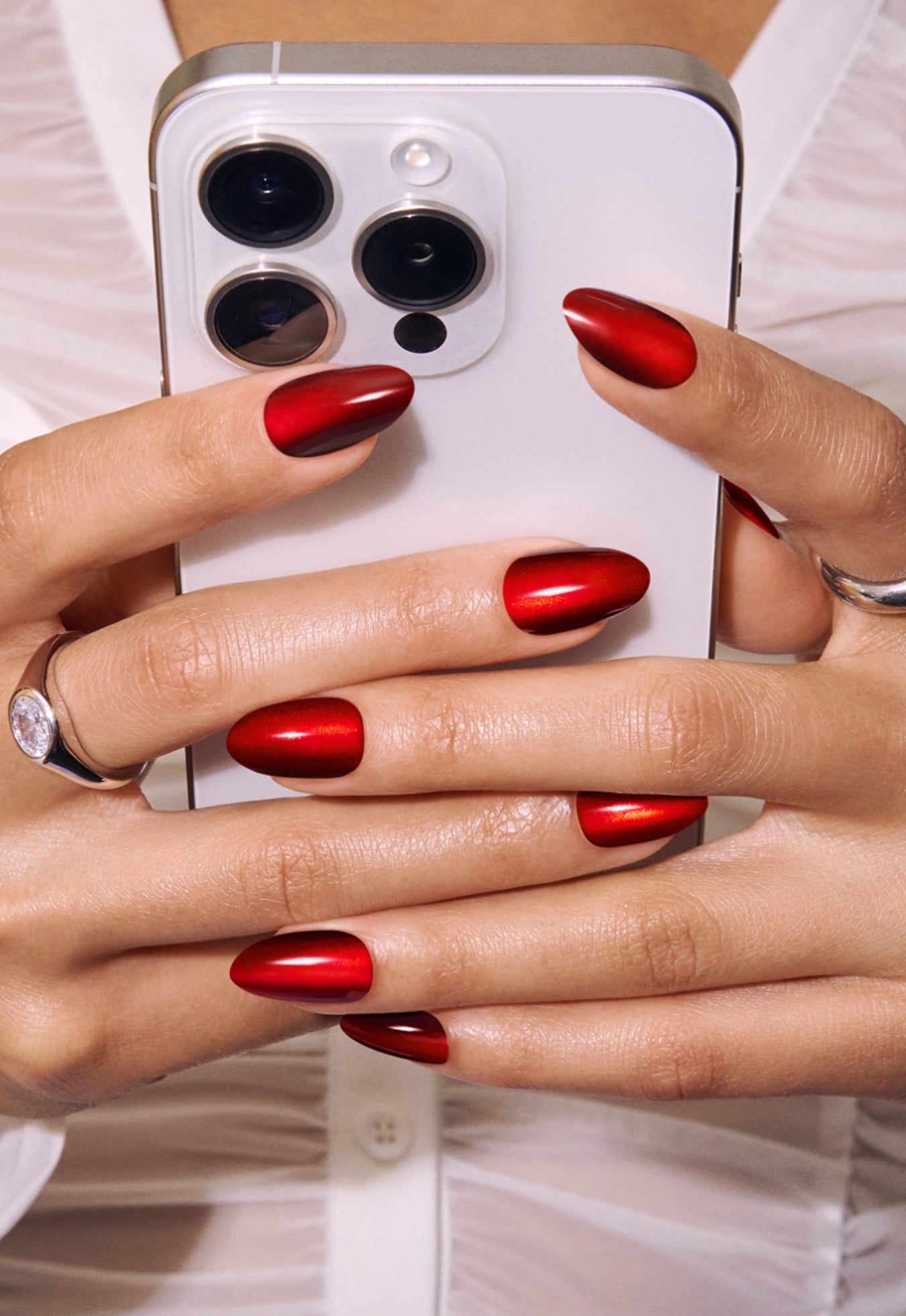 Close-up of hands with red nail polish holding a white smartphone.