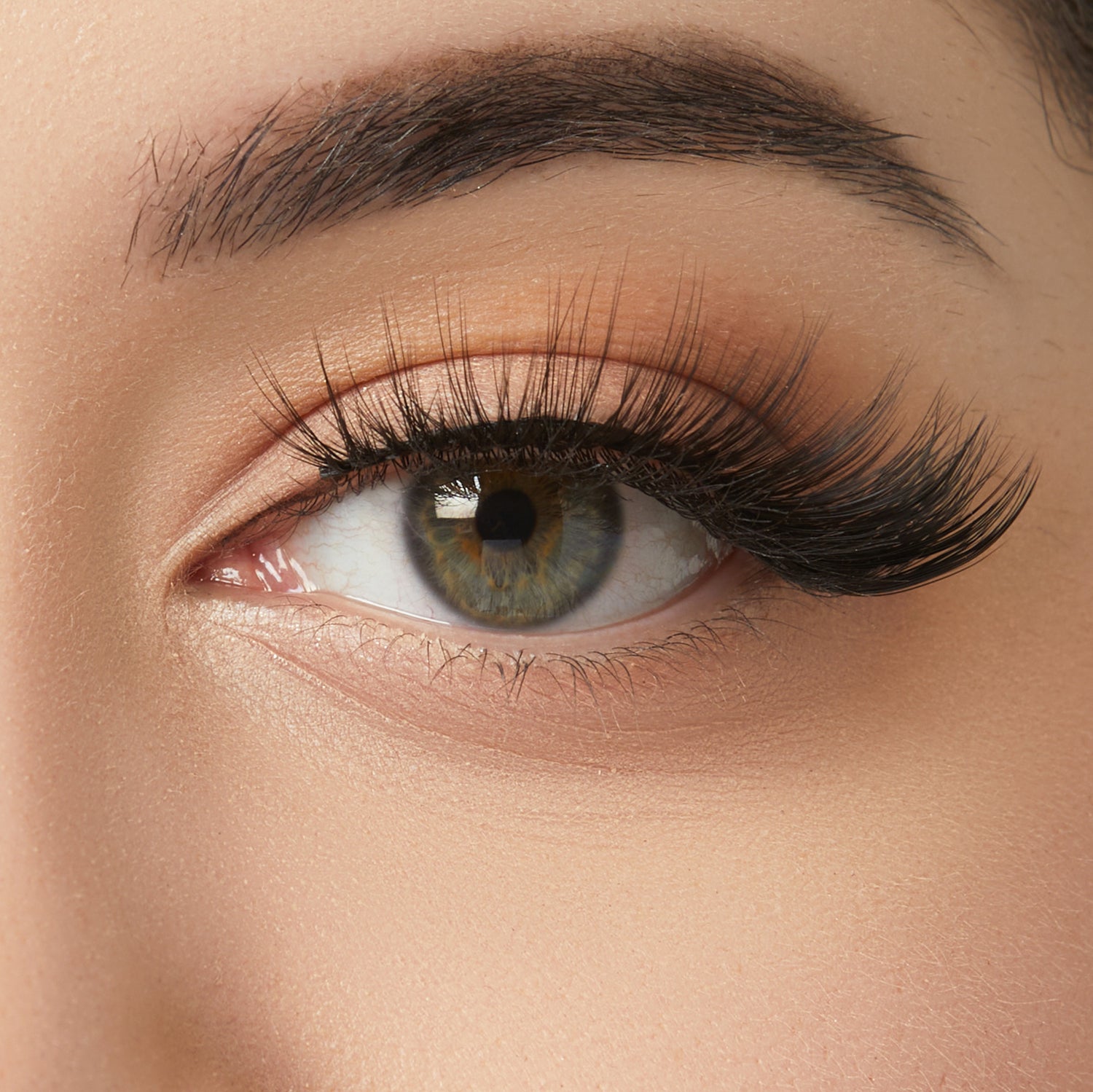 Close-up of eye with warm peachy eyeshadow, dark winged eyeliner, and volumized lashes