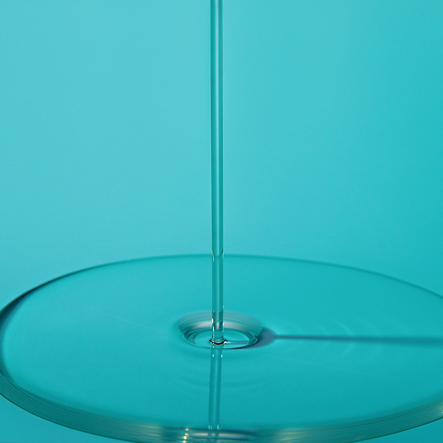 Close-up of a turquoise glass object with a central rod on a solid turquoise background