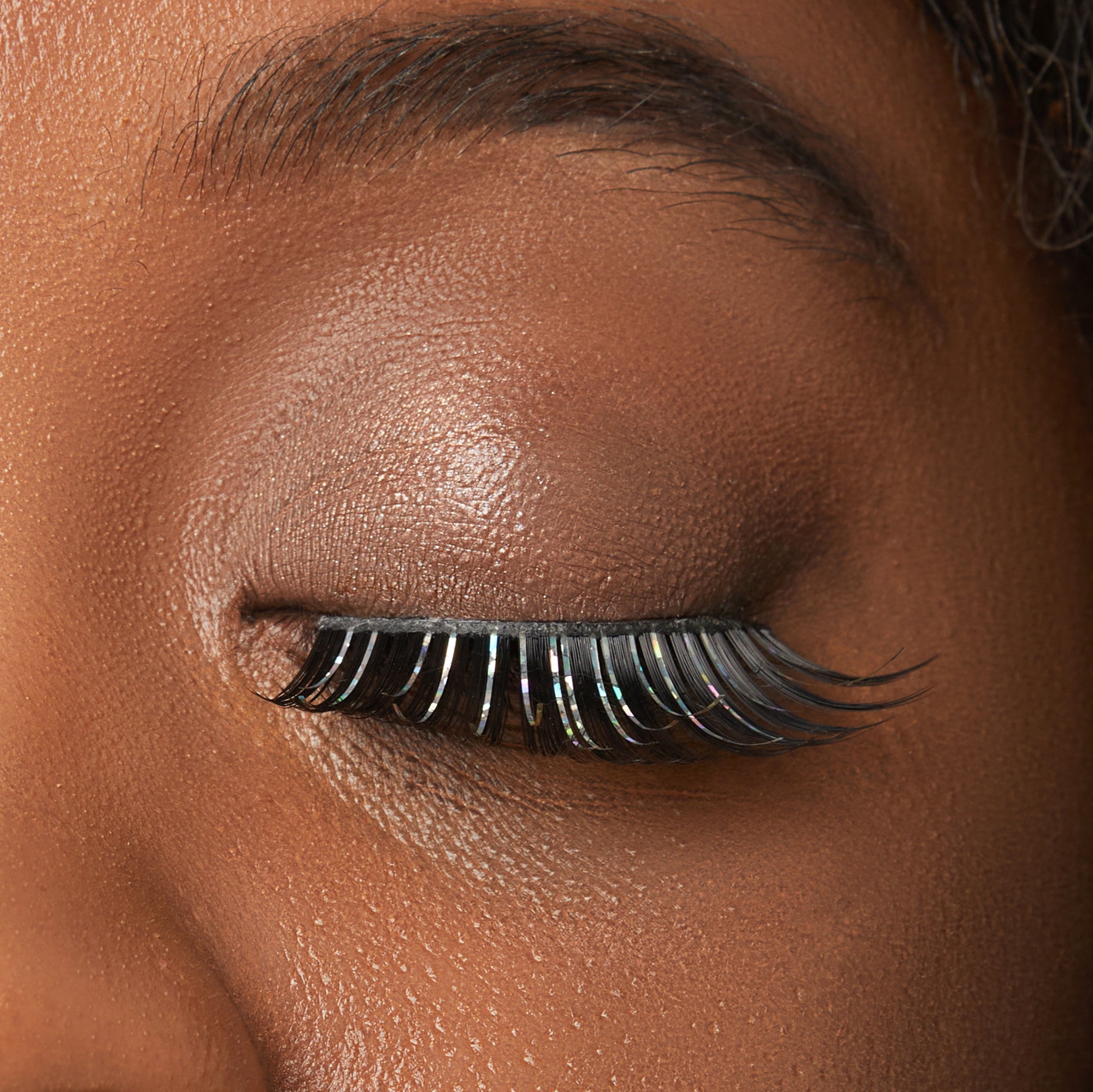Close-up of false eyelashes on closed eye with shimmer eyeshadow