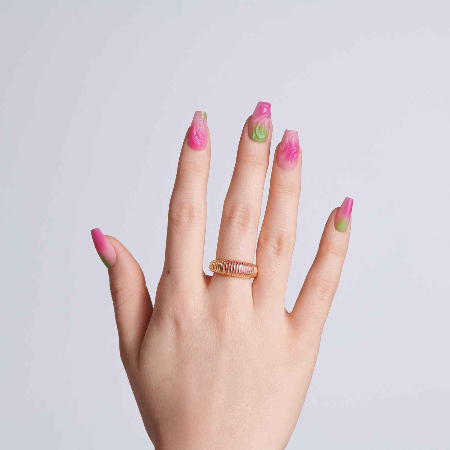 Hand with pink and green nail polish on a plain background