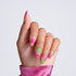 Hand with medium coffin-shaped nails featuring pink and green marble swirl designs and gold accents, wearing a gold ring, against light gray background
