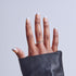Hand with white French manicure nails and DNA helix ring emerging from black leather pouch.