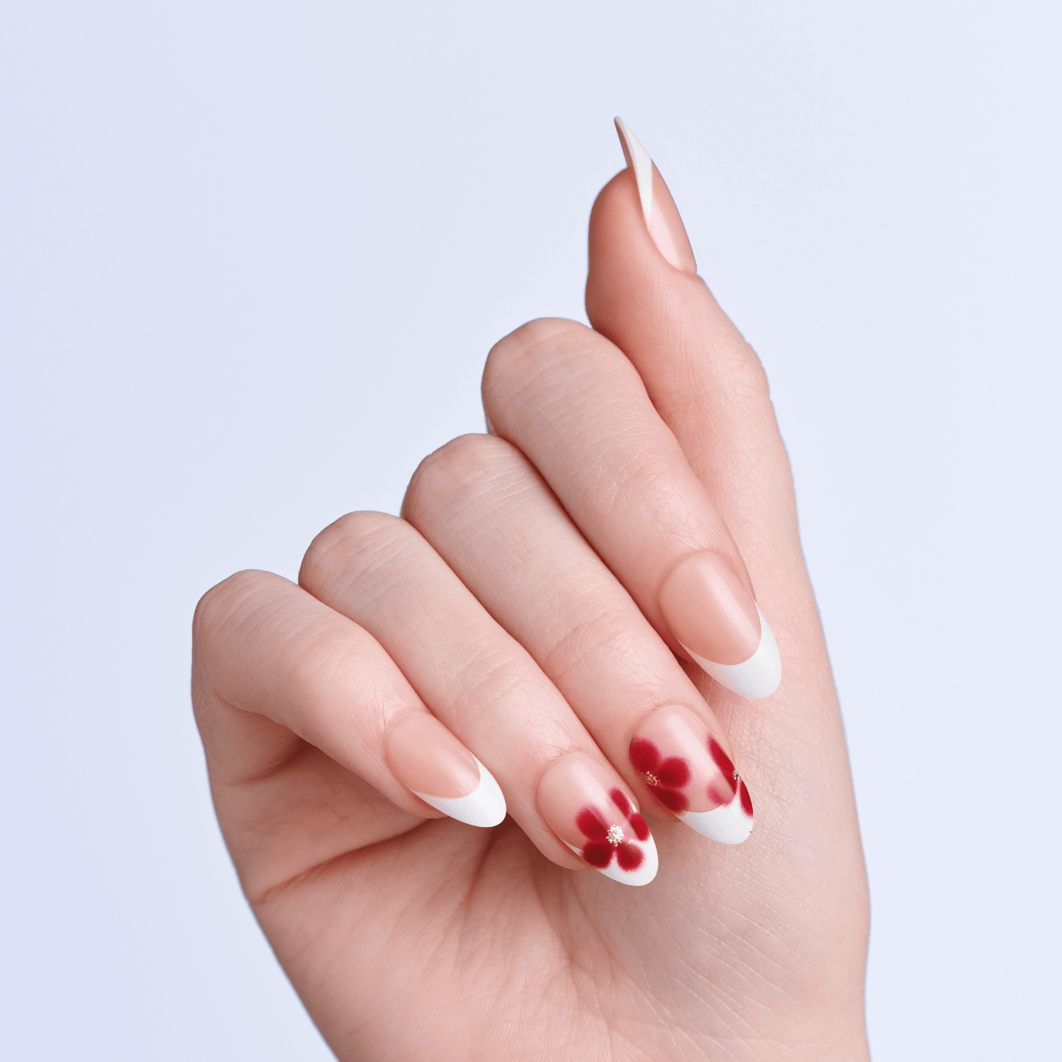 Hand with red and white nail polish on a light gray background