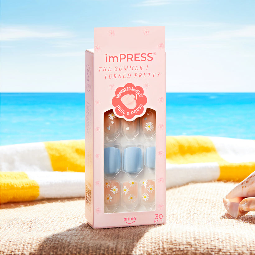 imPRESS press-on nails in beach-themed designs on sandy shore with ocean background.