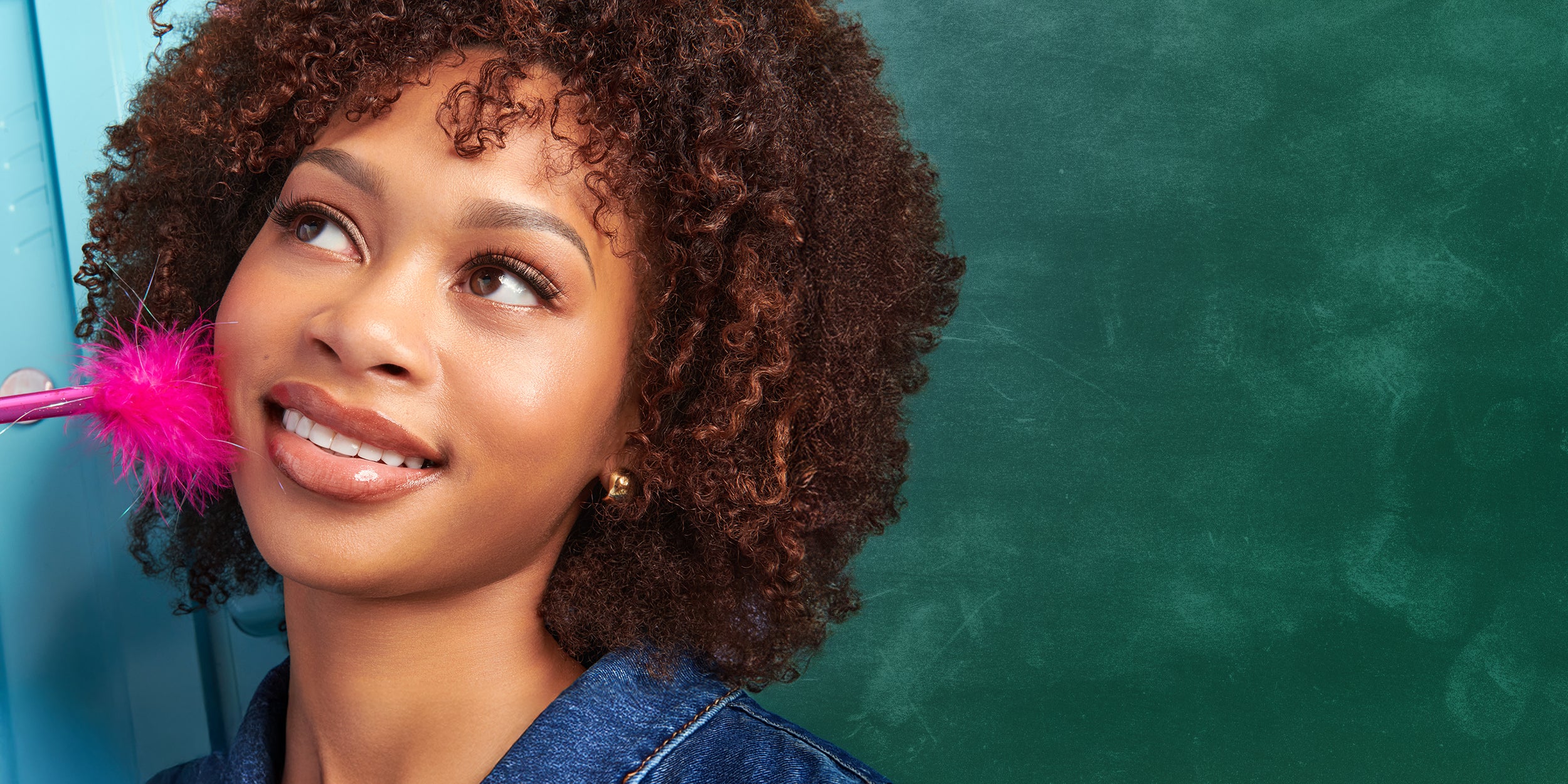 Woman with pink feather in hair against a green chalkboard background