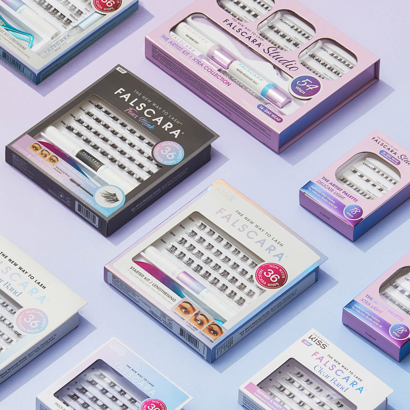 Flat lay of various KISS Falscara lash extension kits arranged on a lavender surface. Each box contains lash clusters and bonding tools, with color-coded packaging like pastel pink, purple, blue, and black. Labels highlight features like “36 Mega Wisps” and “The Artist Kit.”
