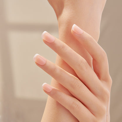 Nude ombre press-on nails with white tips on model hand