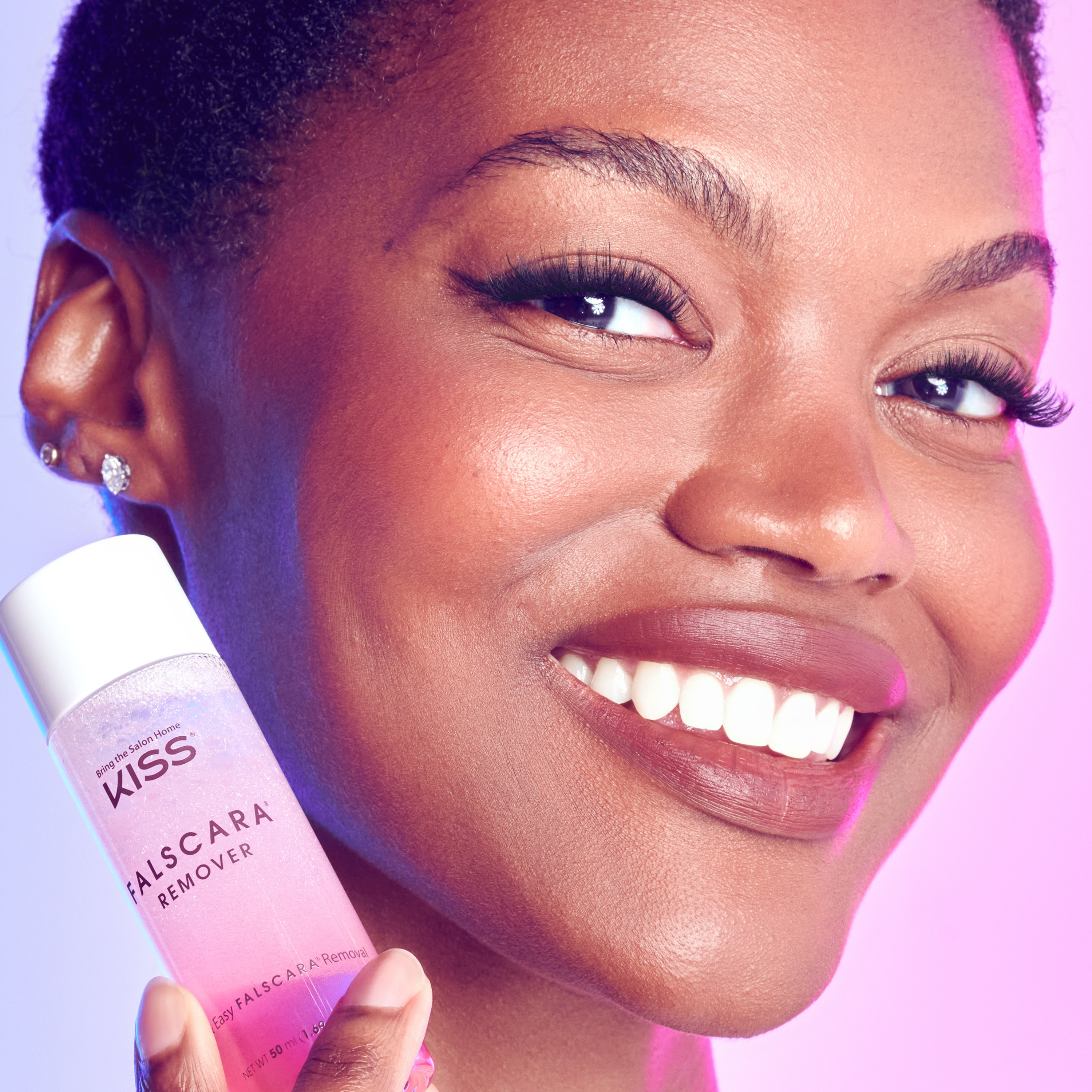 Woman holding a bottle of Kiss Falscara Remover with a close-up of her face.
