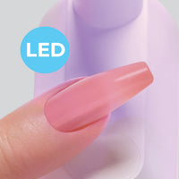 Close-up of artificial nail placed on natural nail curing under the Kiss Salon X-tend LED lamp.