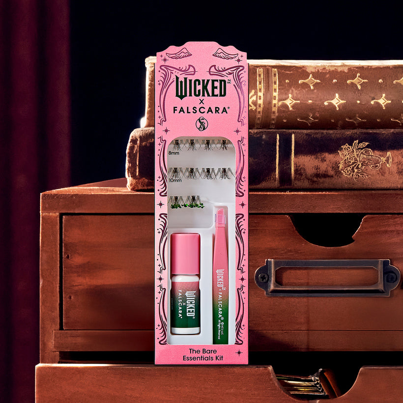 Wicked x FalseCARA The Bare Essentials Kit with false lashes and mascara on wooden drawers.