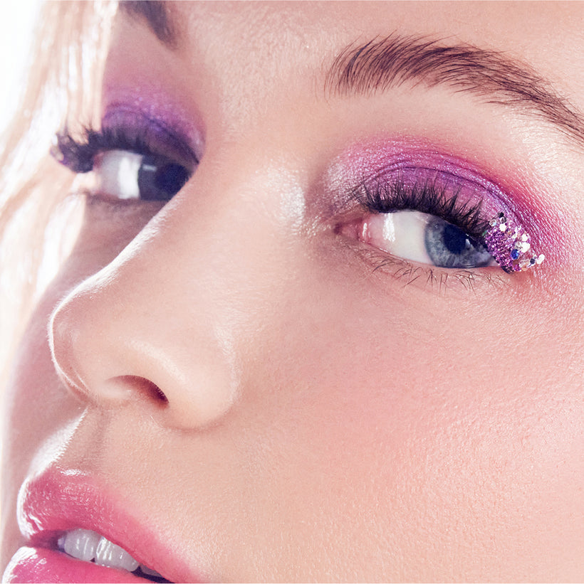 Close-up of model with pink glitter eyeshadow, winged eyeliner, and pink lipstick.