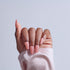 Hand with pink acrylic nails in coffin shape against light blue background
