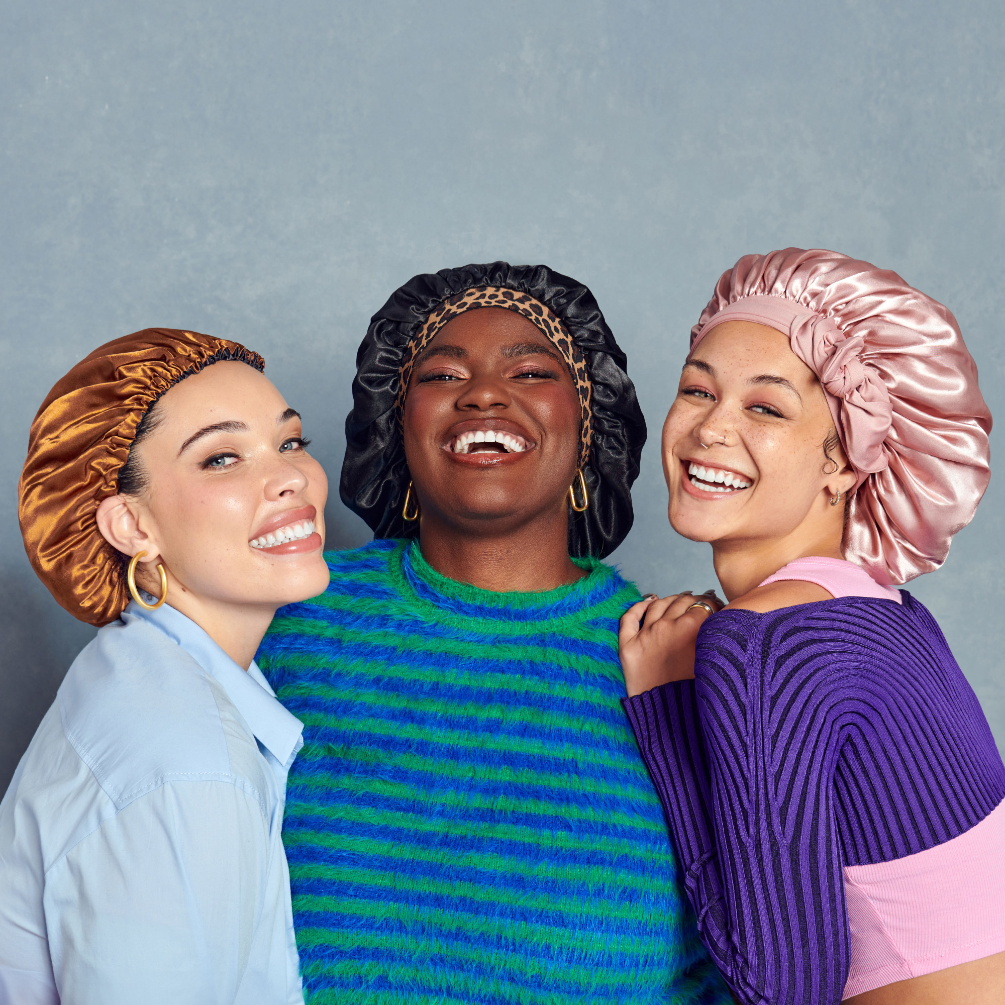 Three women wearing satin headbands against a gray background