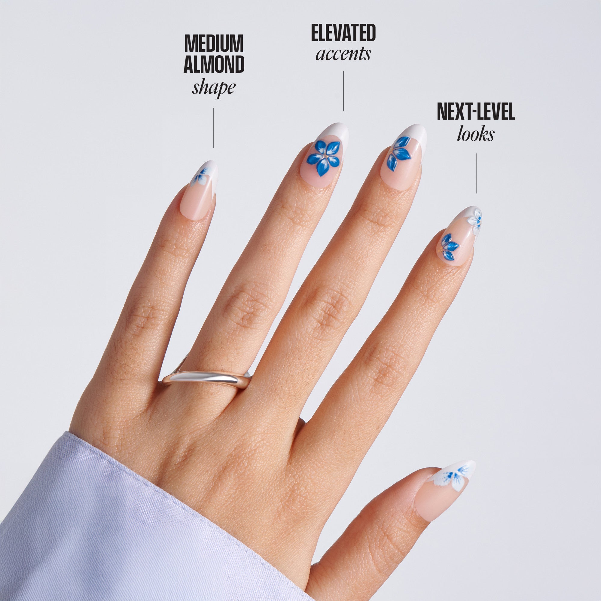 Hand with almond-shaped nails featuring blue floral designs on a light gray background.